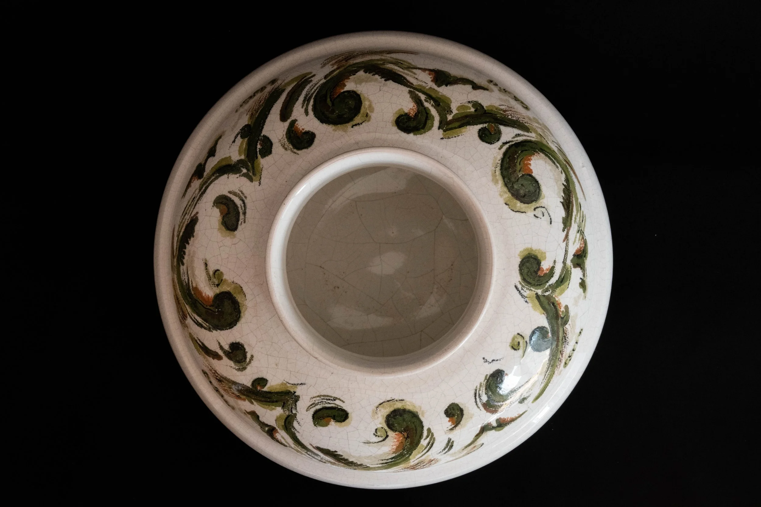 Top view of a decorative ceramic bowl with a floral design on a black background.