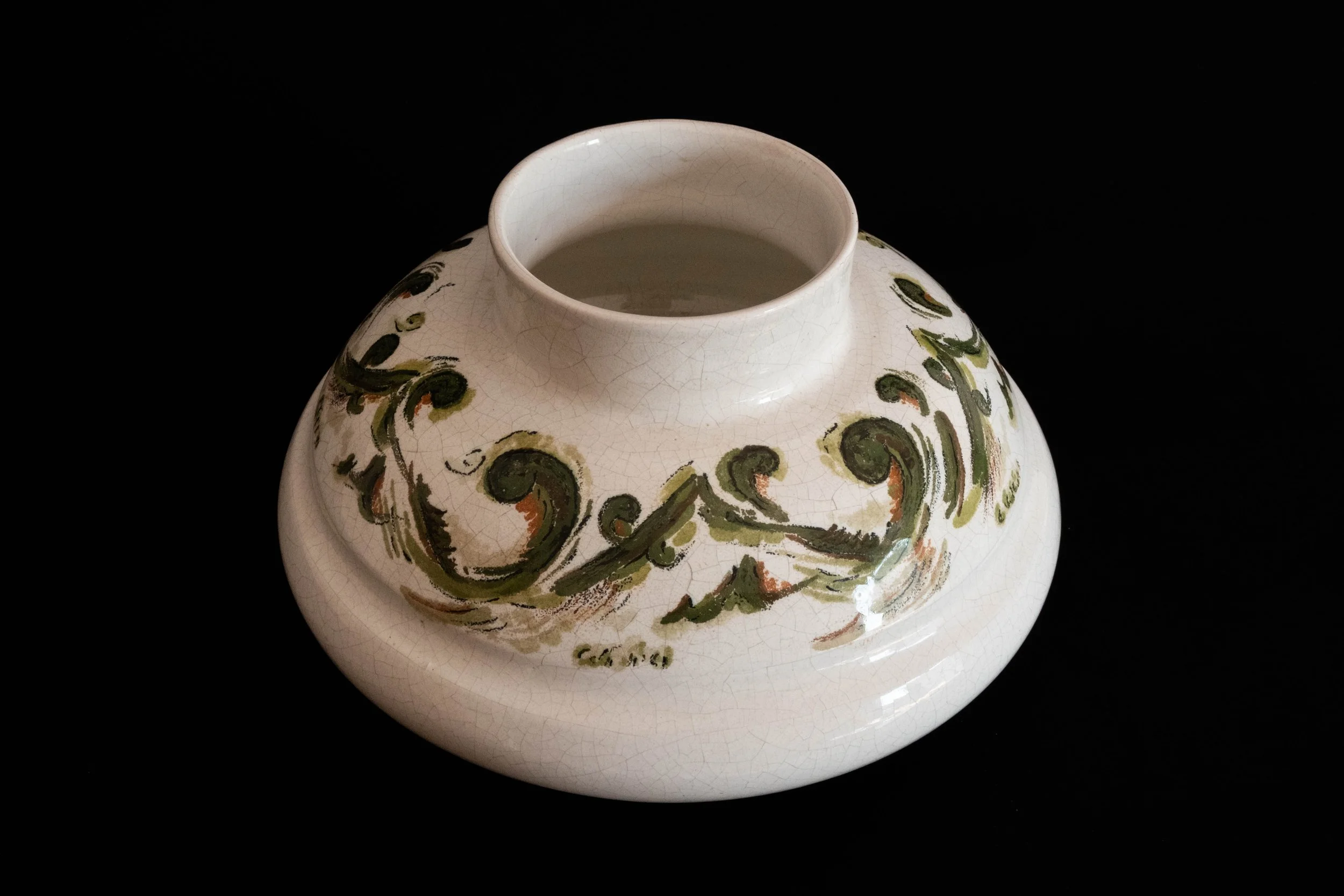 Ceramic vase with abstract green, brown, and black brushstroke designs on a white cracked glaze surface, set against a black background.