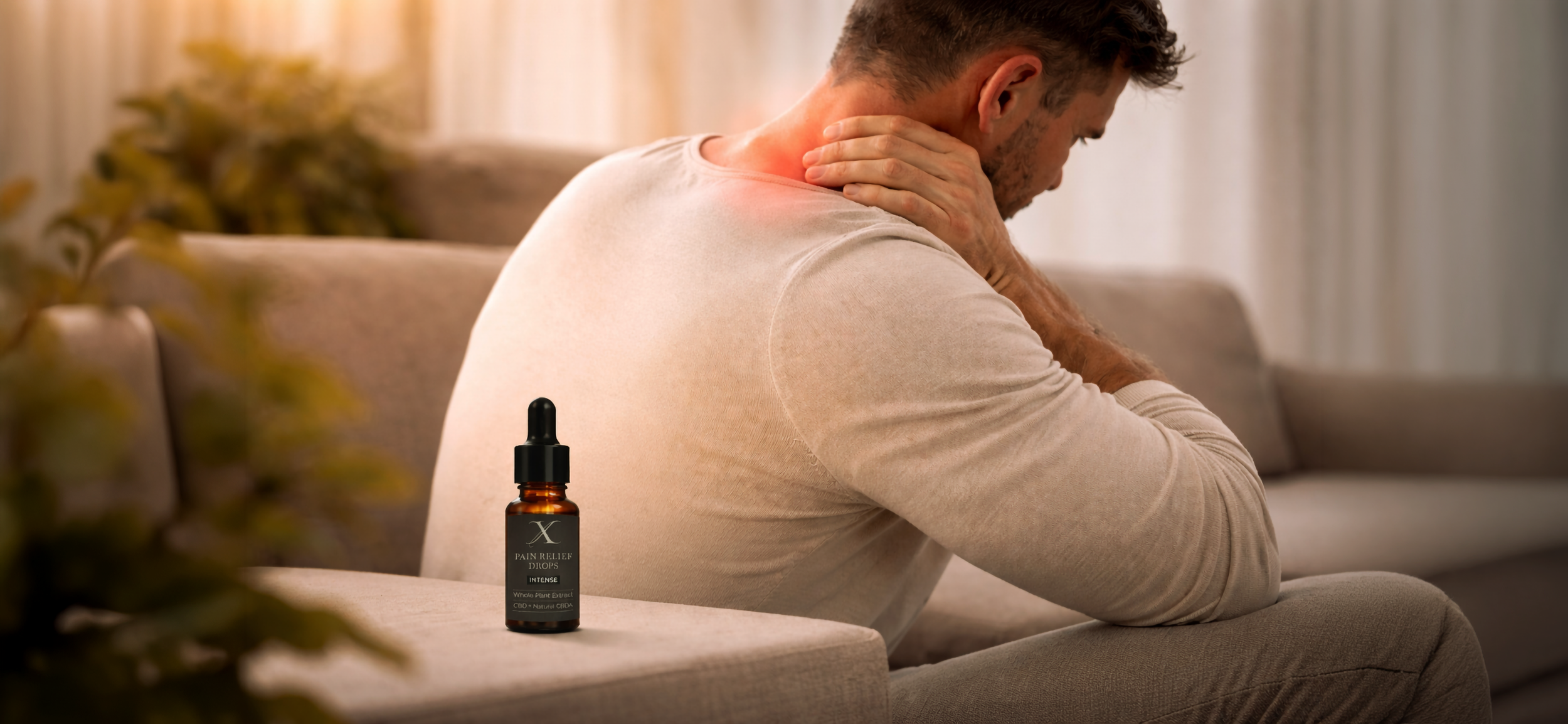 Mand, der sidder på en sofa og holder sin nakke, med en flaske CBD olie placeret foran ham på sofabordet.