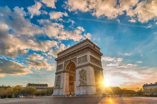 L'arc de Triomphe à Paris vu lors du coucher de soleil, avec un ciel partiellement nuageux.