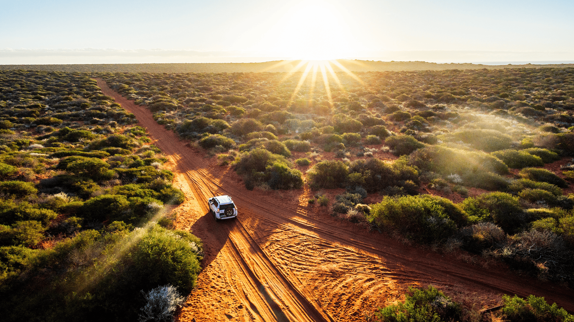 Een 4x4 auto rijd over een zandweg door de Australische outback