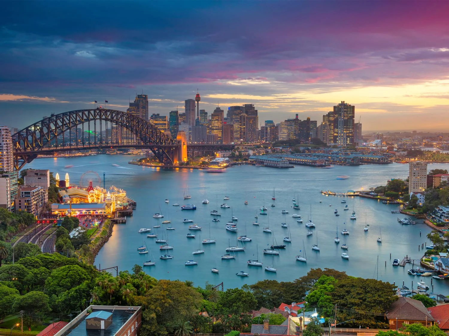 Downtown Sydney skyline met de harbour bridge, sydney operahouse and sydney skyline tijdens zonsondergang met boten in de baai