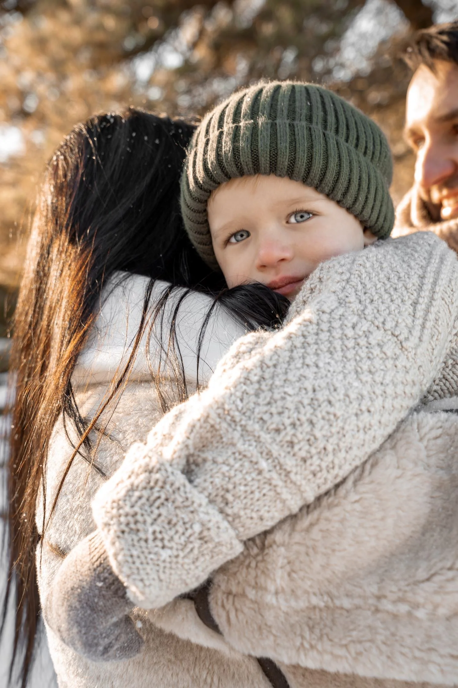 Dreng som krammer mor til familiefotografering i naturen nordsjælland københavn med grøn hue og beige striktrøje