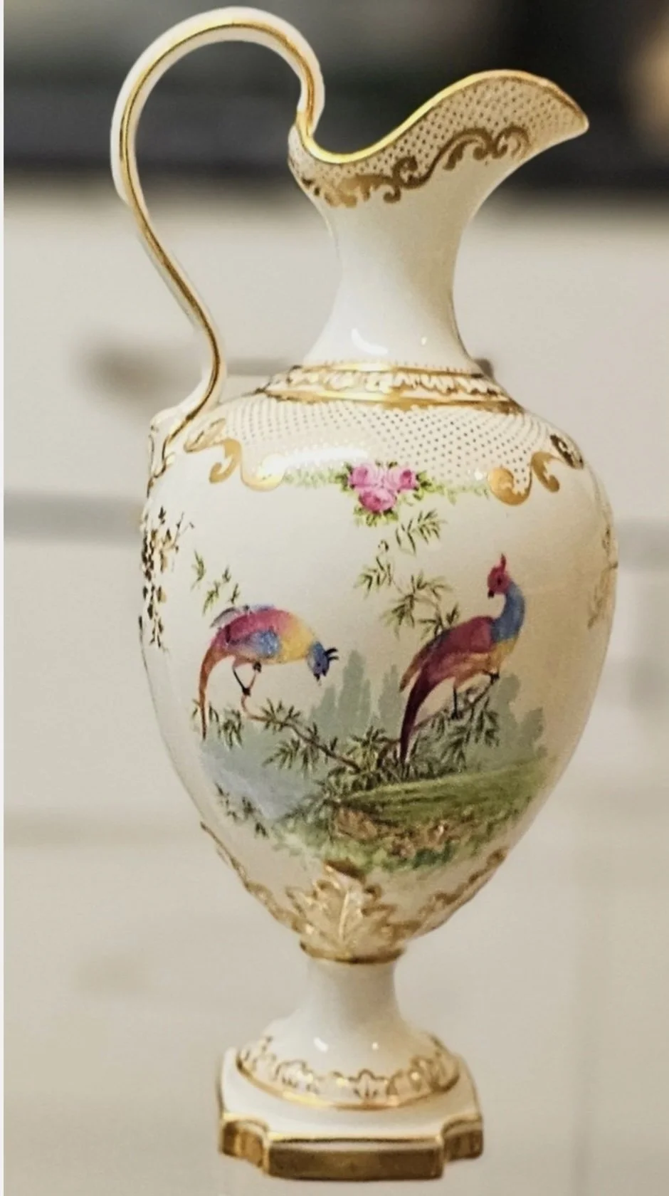 Decorative porcelain vase with gold accents, featuring colorful painted birds and greenery.