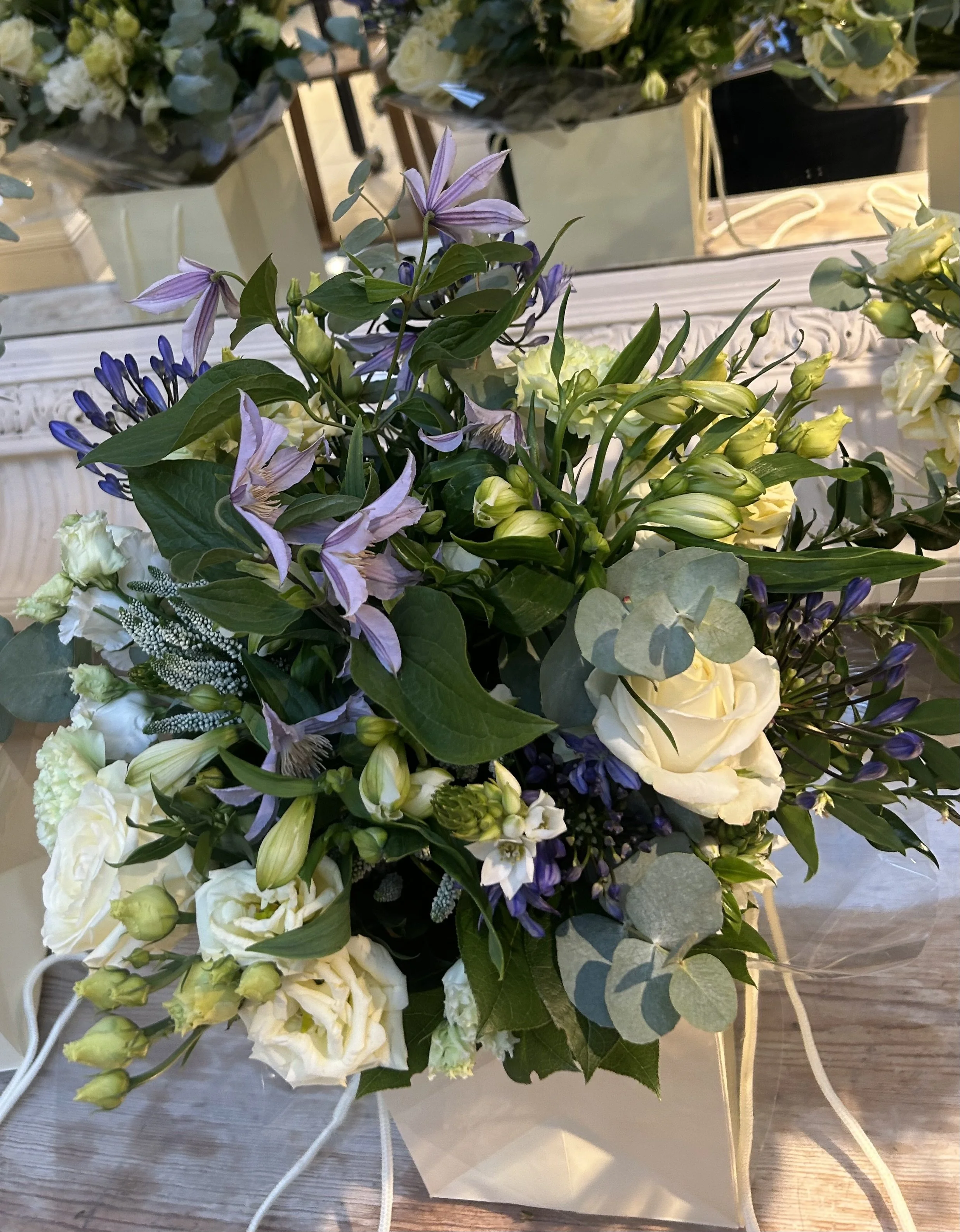 This lush garden to vase bouquet from Heirloom Plume and Petal blends cool violet tones with timeless ivory blooms that radiates sophisticated charm.