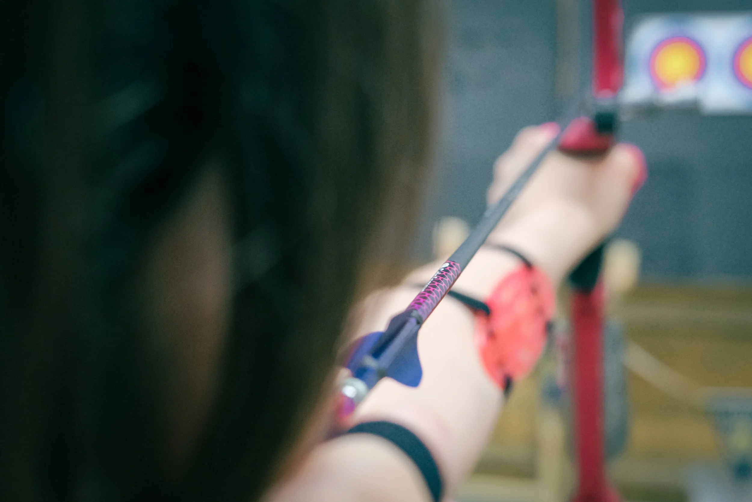 A person is aiming a bow and arrow at an archery target.