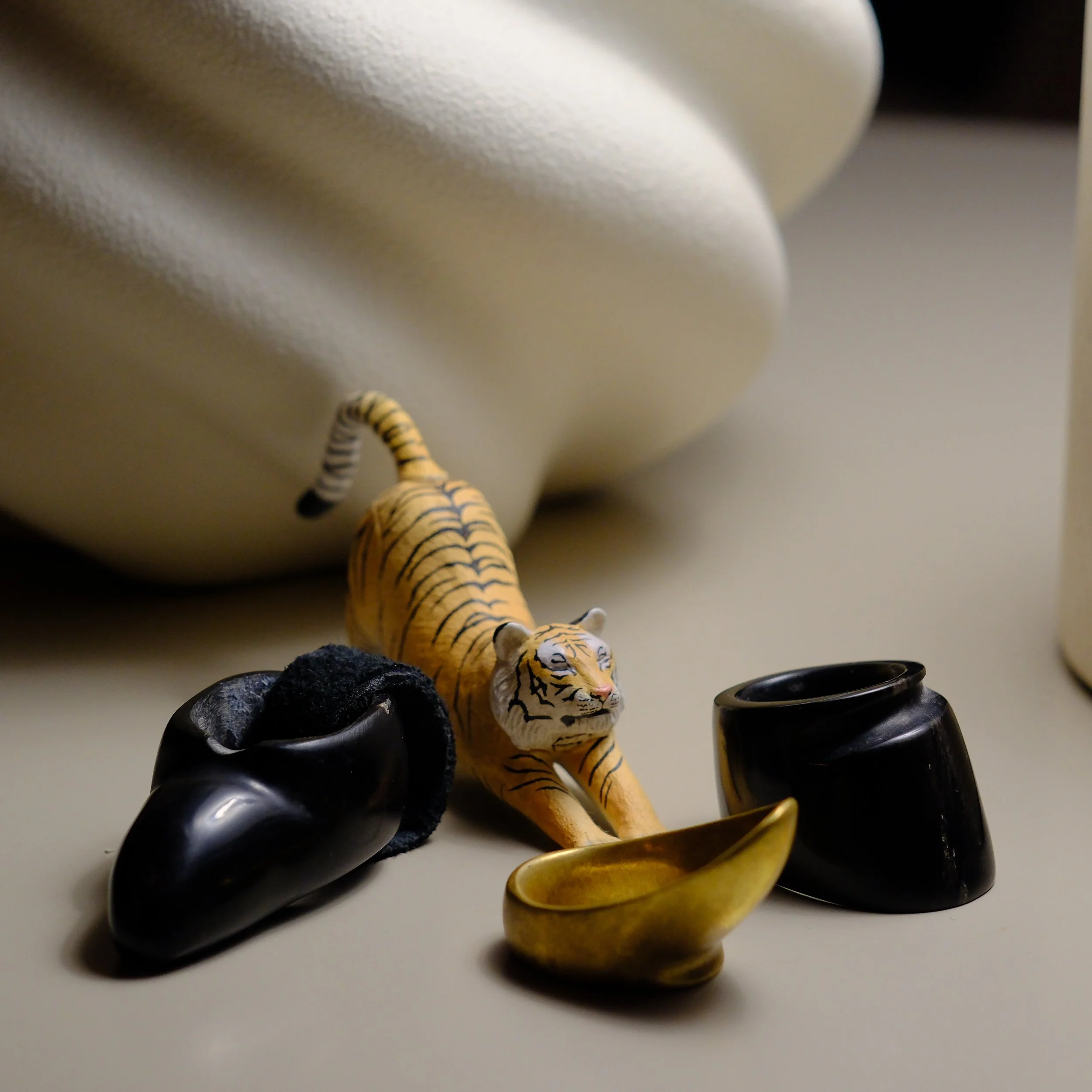 Small toy tiger surrounded by three thumb rings for traditional Asiatic Archery