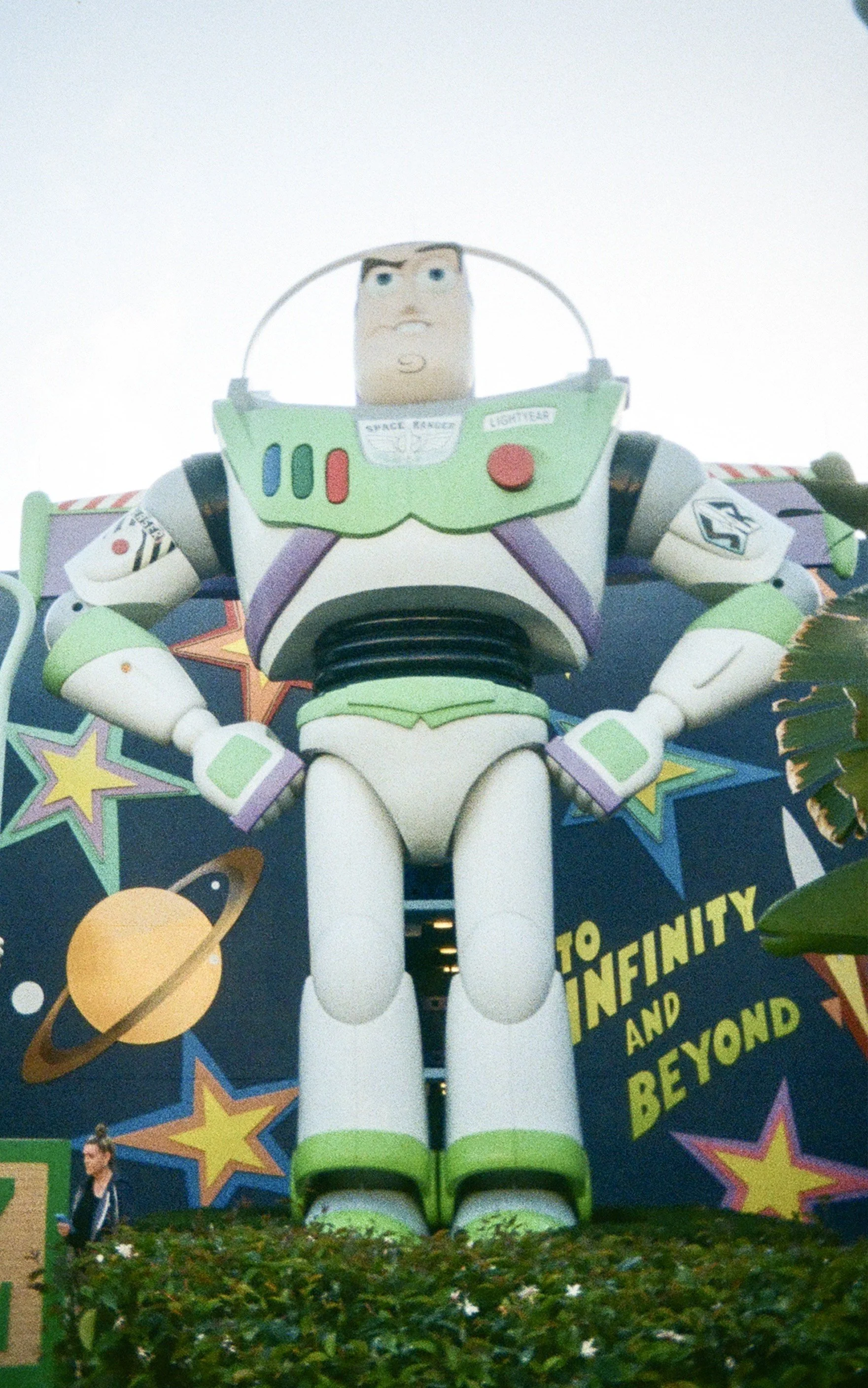 Large Toy Story Buzz Lightyear statue outside of a themed attraction with galaxy and star decorations, and 'To Infinity and Beyond' sign.