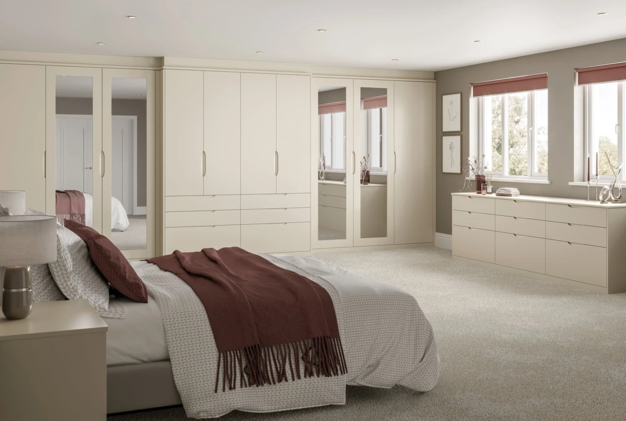 A modern bedroom with light-colored furniture, a bed with pillows and a throw blanket, large windows with blinds, and a carpeted floor.