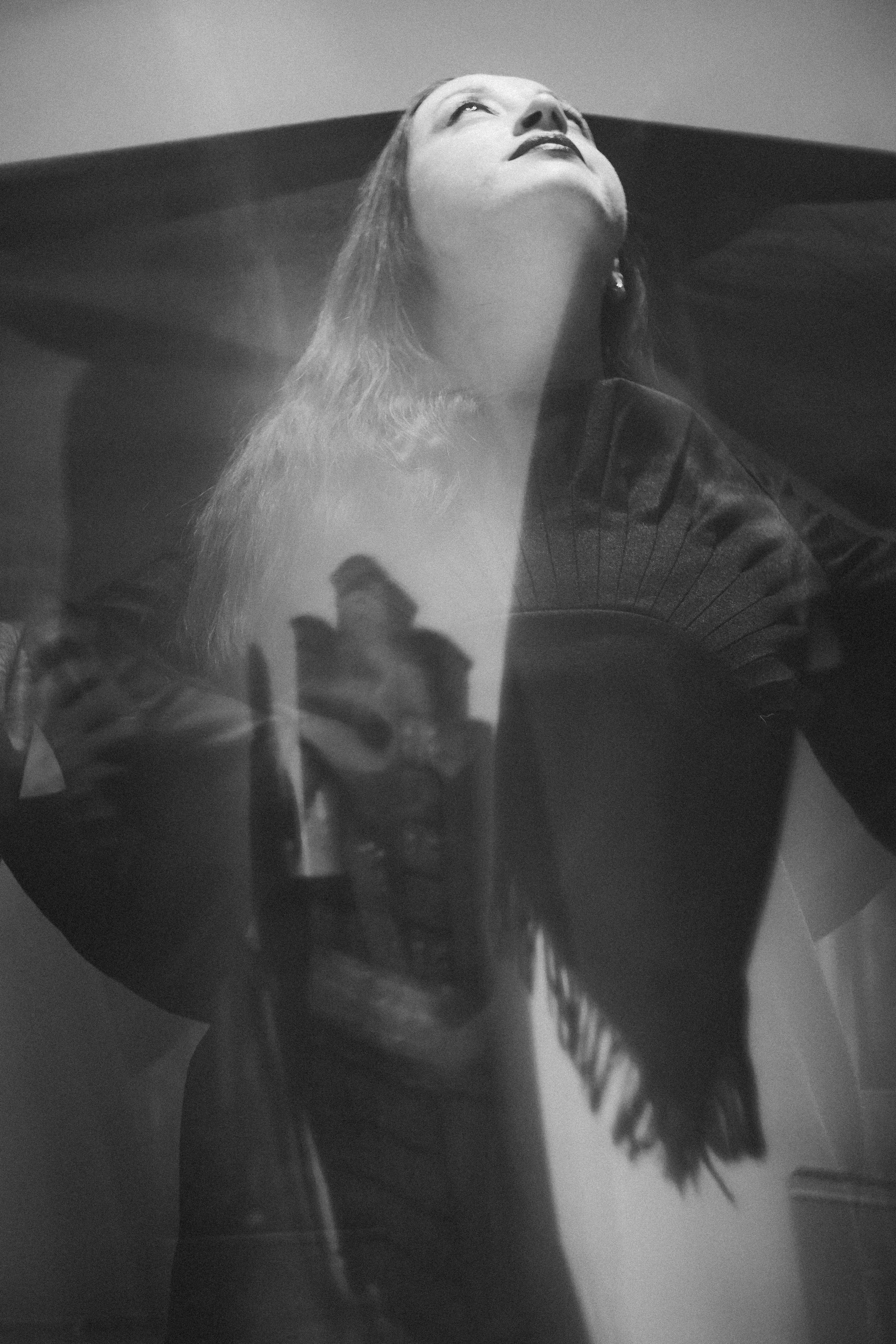 Black and white portrait of a woman looking upwards with reflections of city buildings on her face - fine art photography