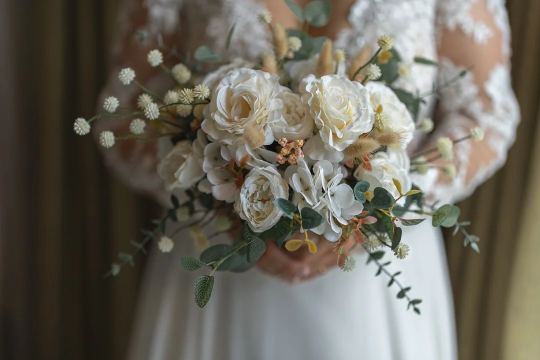 A bride holding a bouquet of white flowers and greenery.