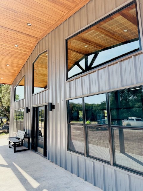 Exterior of a modern building with large windows, metal siding, and a wooden overhang roof
