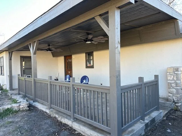 APEX LAND & CONSTRUCTION WEST TEXAS | OZONA | SONORA 76943  Back porch of a house with a wooden railing, ceiling fans, and two chairs.