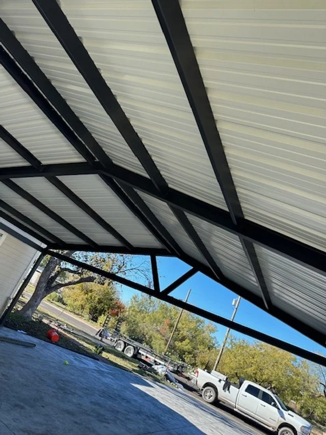 APEX LAND & CONSTRUCTION WEST TEXAS | OZONA | SONORA 76943  View of a metal carport roof with a parking lot and trees in the background.