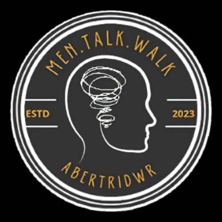 A circular logo with a black background and white and yellow text. The logo features a white outline of a human head with a swirling line inside. The text reads 'MEN. TALK. WALK' at the top, 'ABERTRIDWR' at the bottom, with 'ESTD' on the left and '2023' on the right.