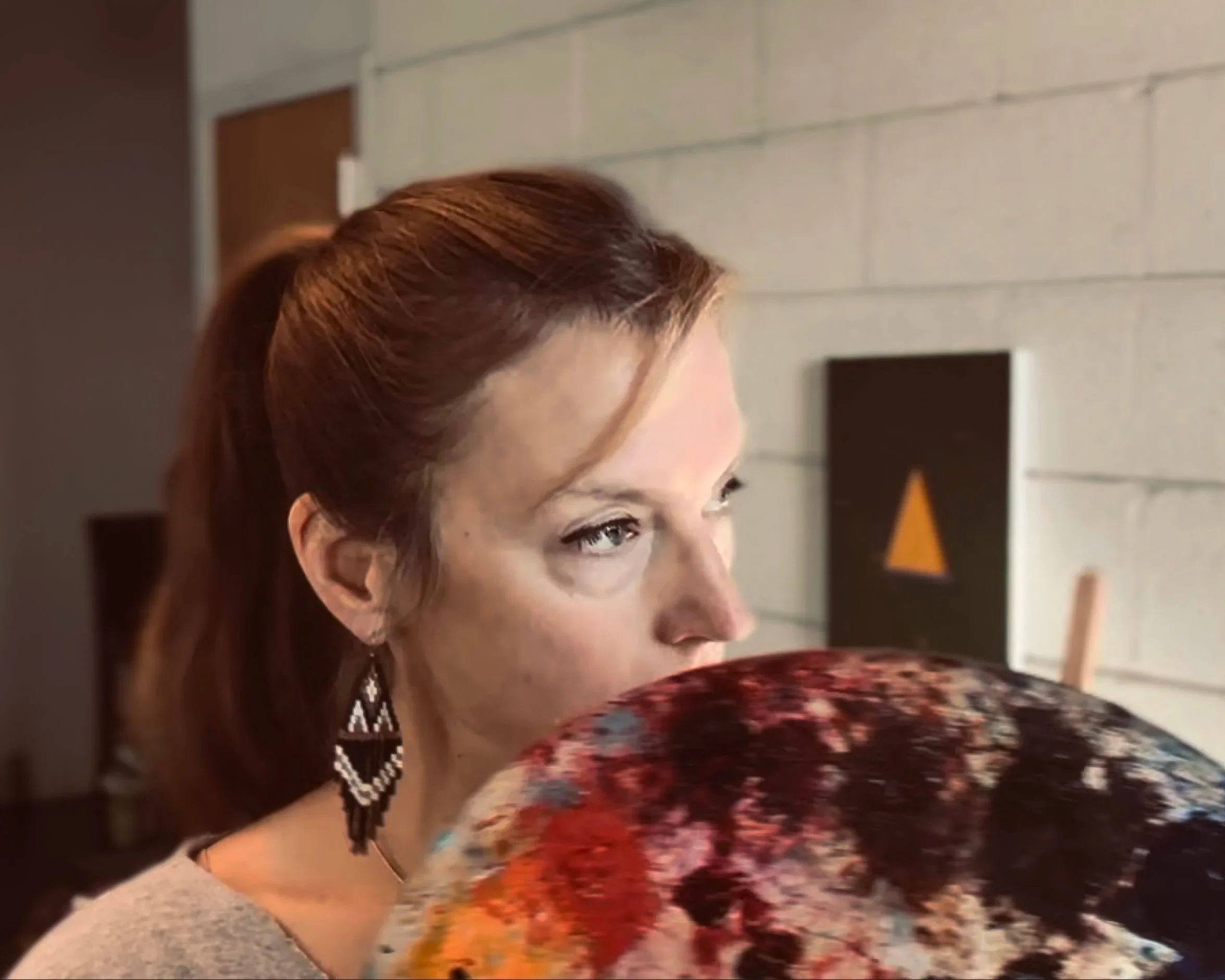 A woman with of a woman looking away with paint palette in front of face