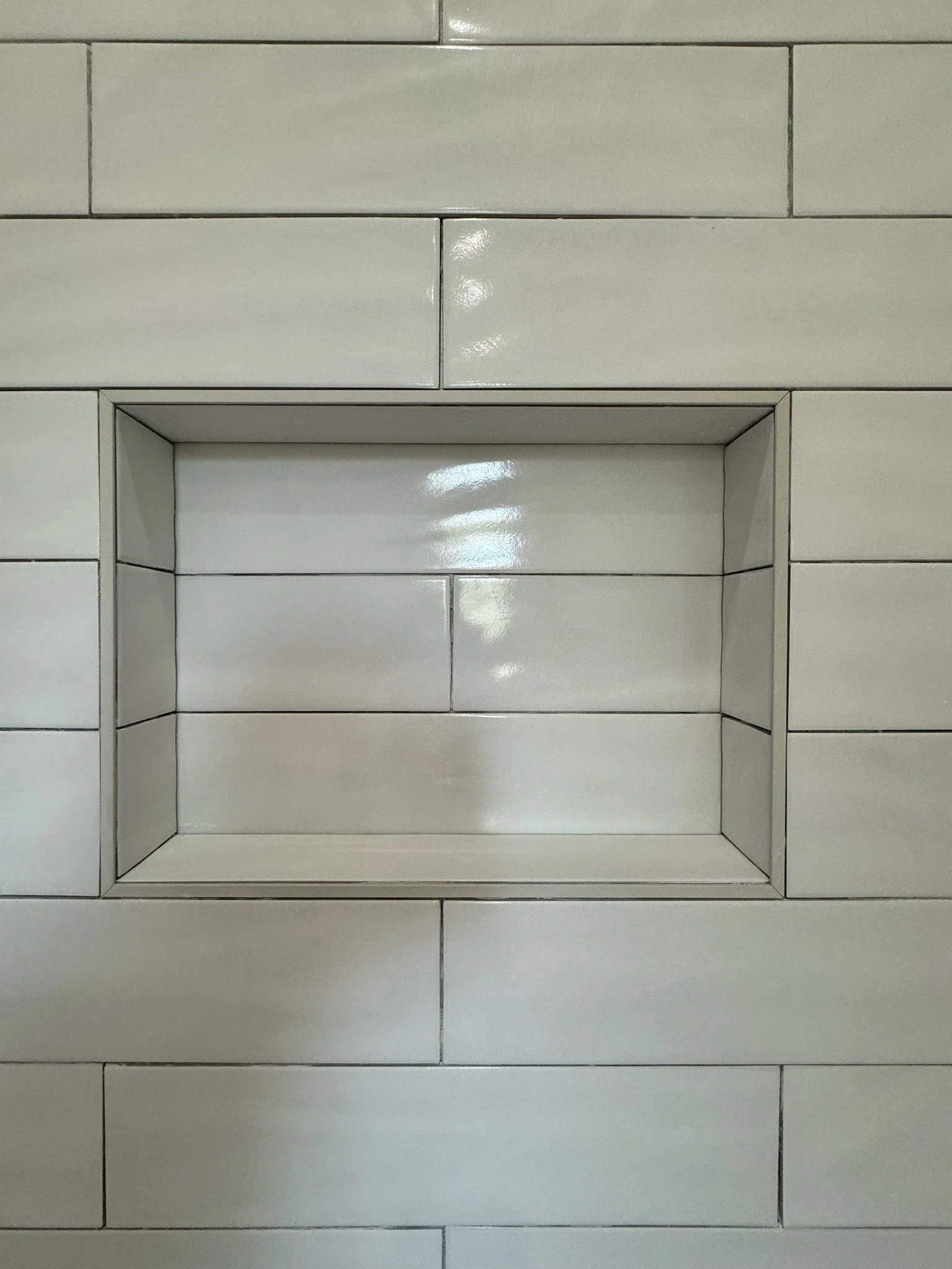 Marble tiled shower with a built-in corner bench and small square wall and floor tiles.