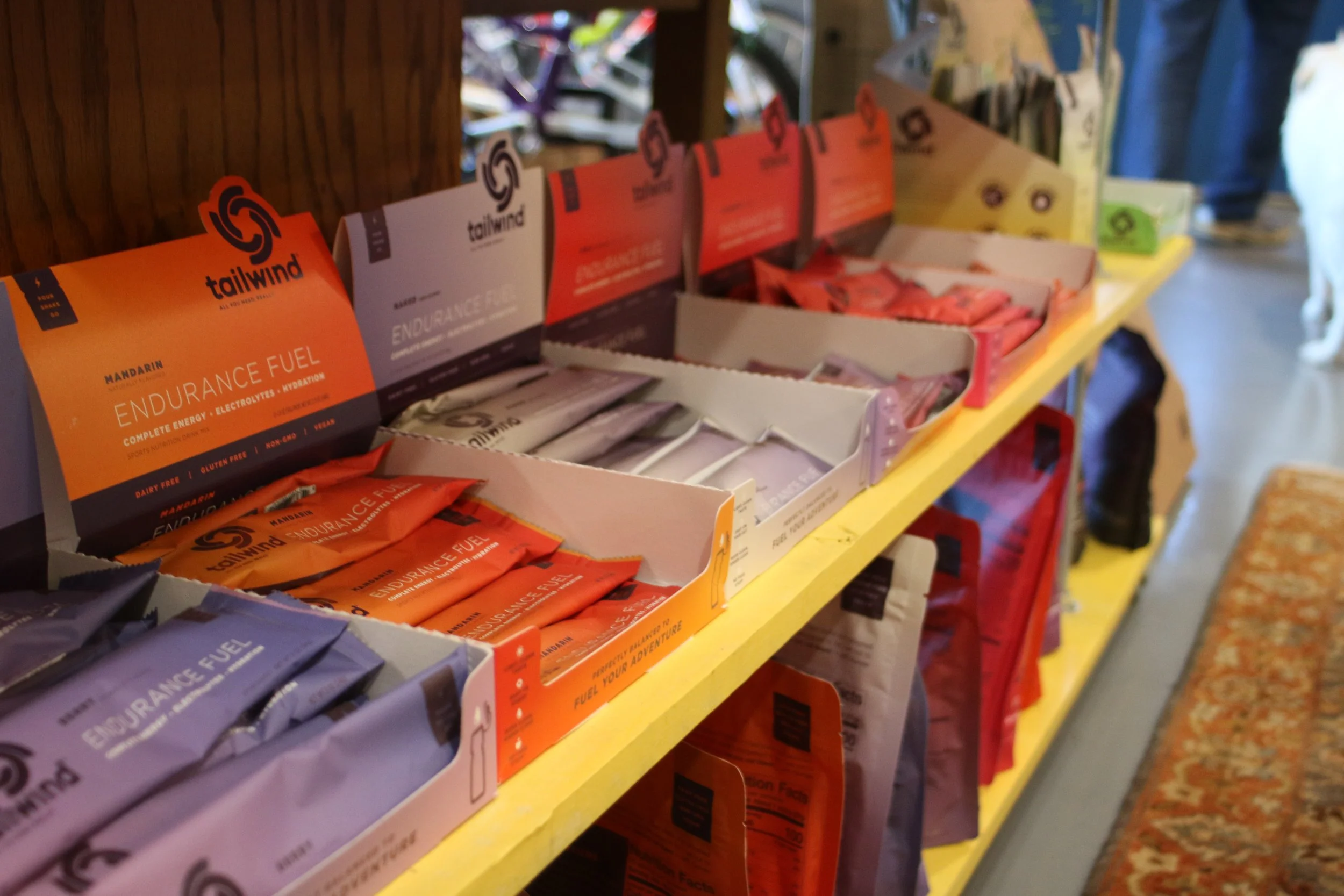 Display of Tailwind energy fuel packets in various flavors on a yellow shelf at a store.