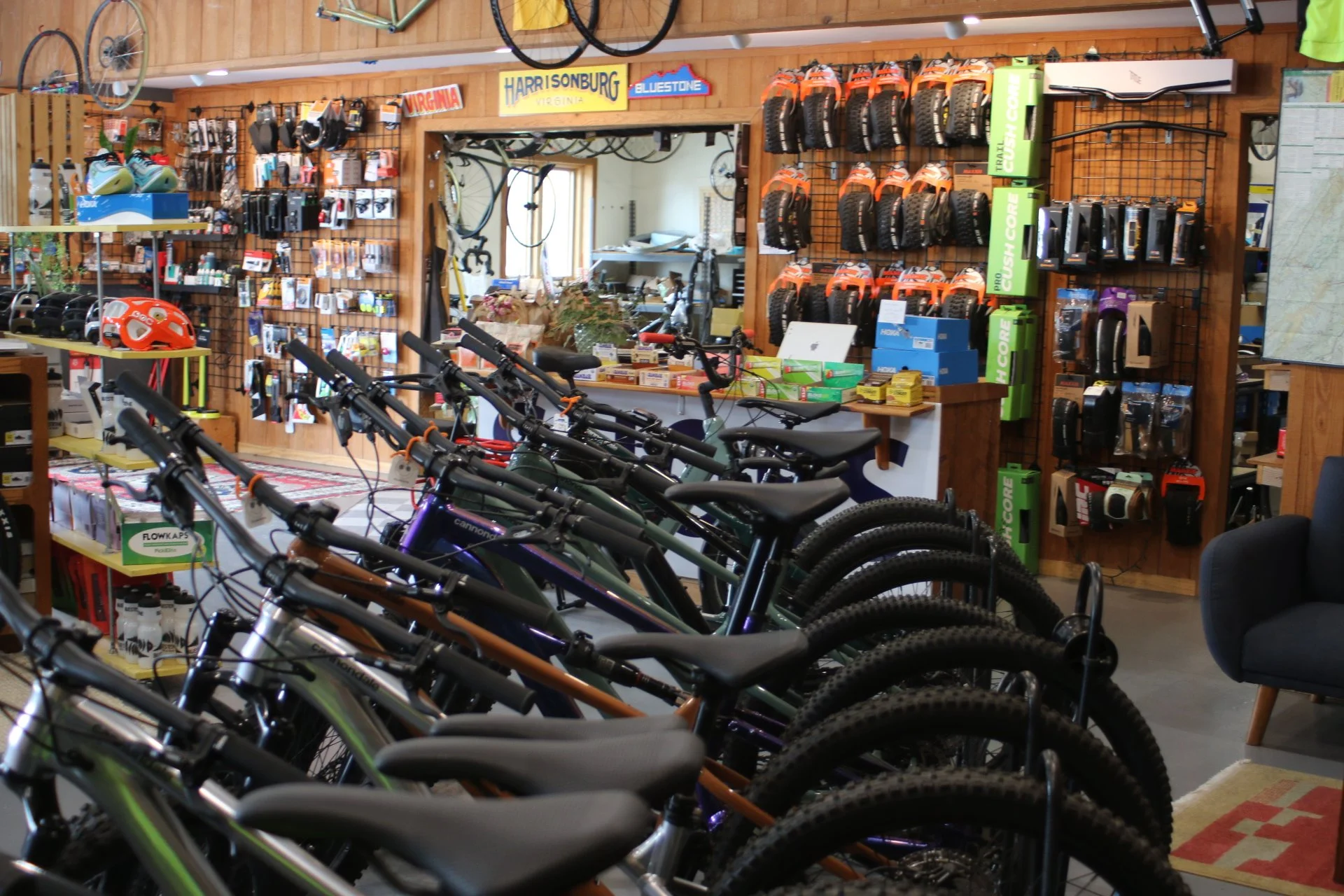 Interior of a bike shop with mountain bikes lined up, wall-mounted helmets, and cycling accessories displayed on the walls.
