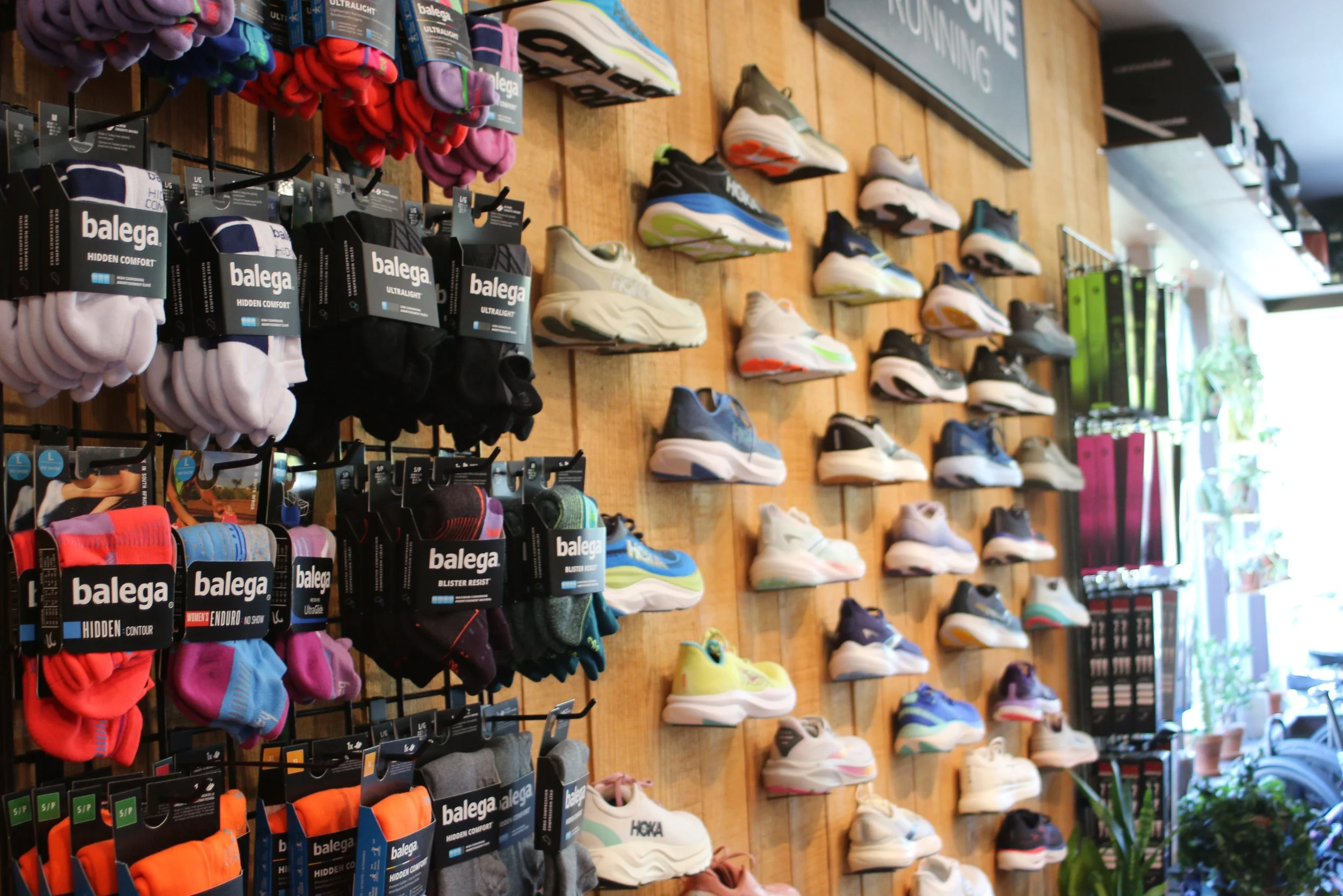 Rack of colorful athletic shoes and socks displayed on a wooden wall in a store.