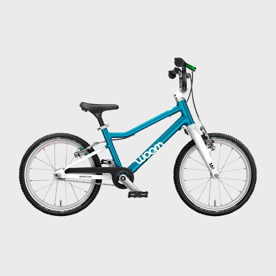 Blue and white Woom children's bicycle with black seat and handlebars on a gray background.