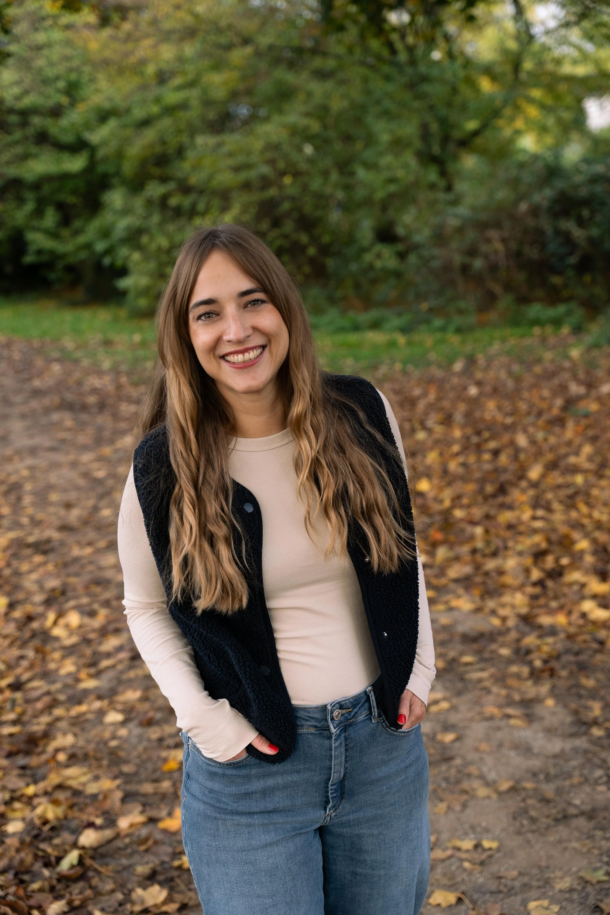 Franzisk Pille steht vor einer Herbstlichen Hecke, Laub liegt auf dem Boden