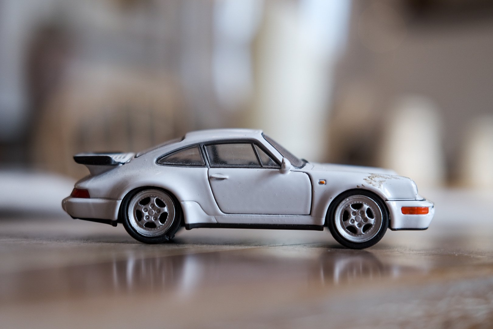 A small silver toy car resembling a classic Porsche sports car.