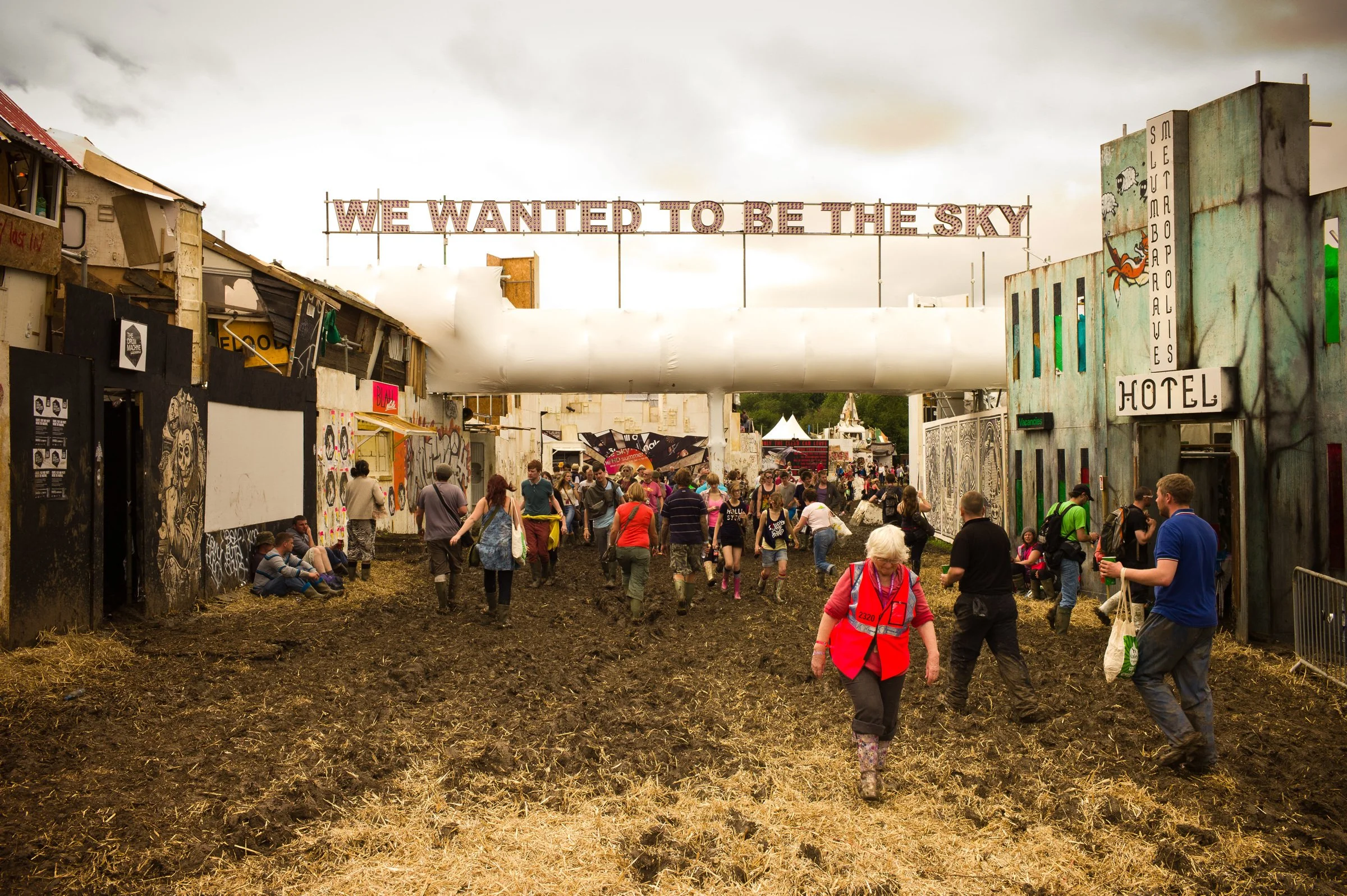 Festivalgoers walking beneath a banner reading We wanted to be the sky