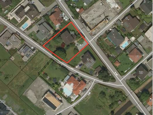 Luftaufnahme eines Grundstücks mit roter Umrahmung in einer Wohngegend, inklusive Häuser, Gärten und Straßen.