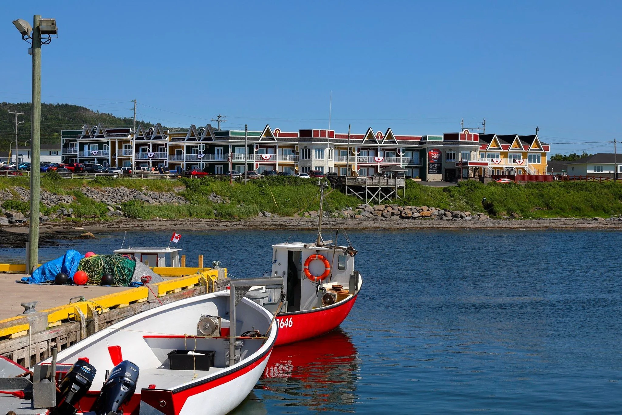 Boats docked at a harbor with a colorful seaside hotel in the background.