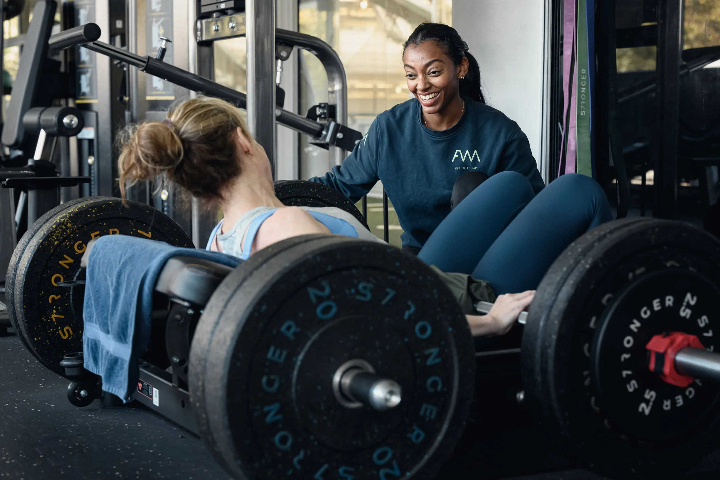 Female lifting weights with personal trainer in gym north west london