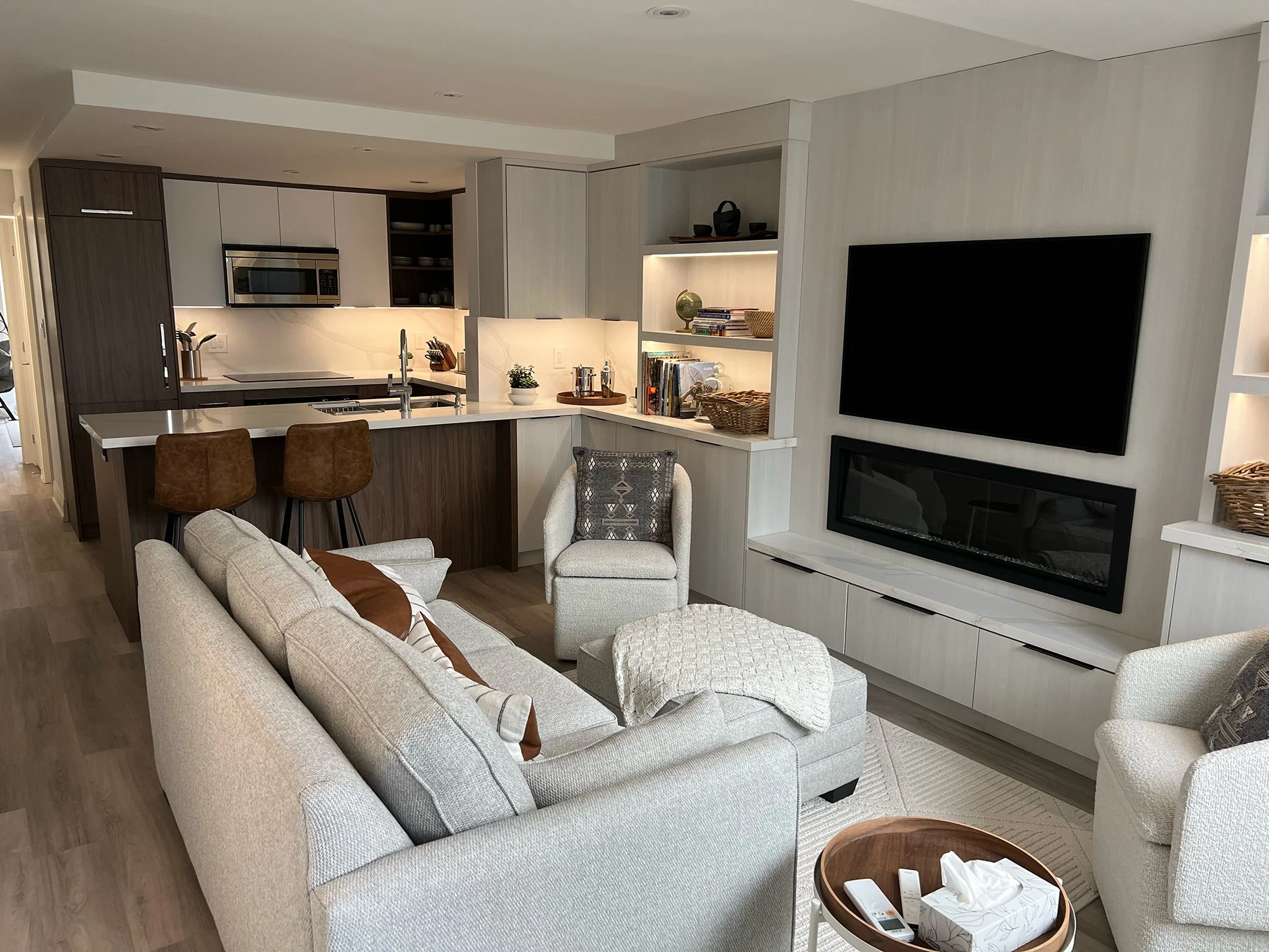 Open-plan living room and kitchen after phased renovation, showing modern finishes and built-in shelving.