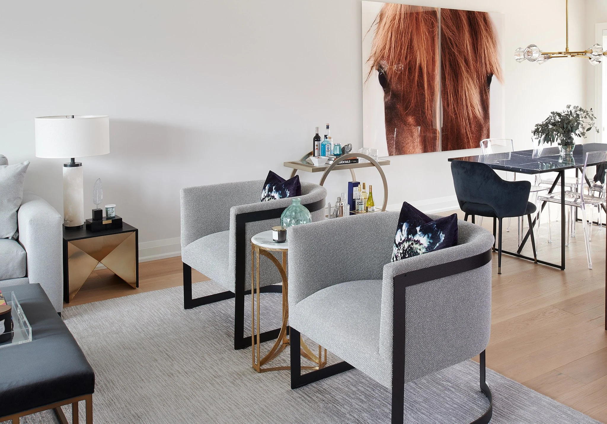 Modern open-concept living and dining room featuring grey textured armchairs, marble accents, and custom wall art by a Toronto home builder.