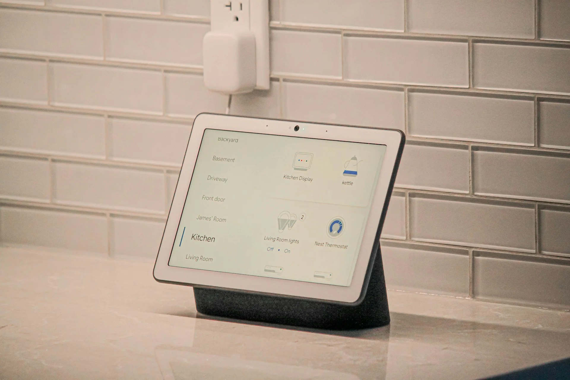 Smart home control tablet showing lighting, climate, and room controls in a custom home kitchen.