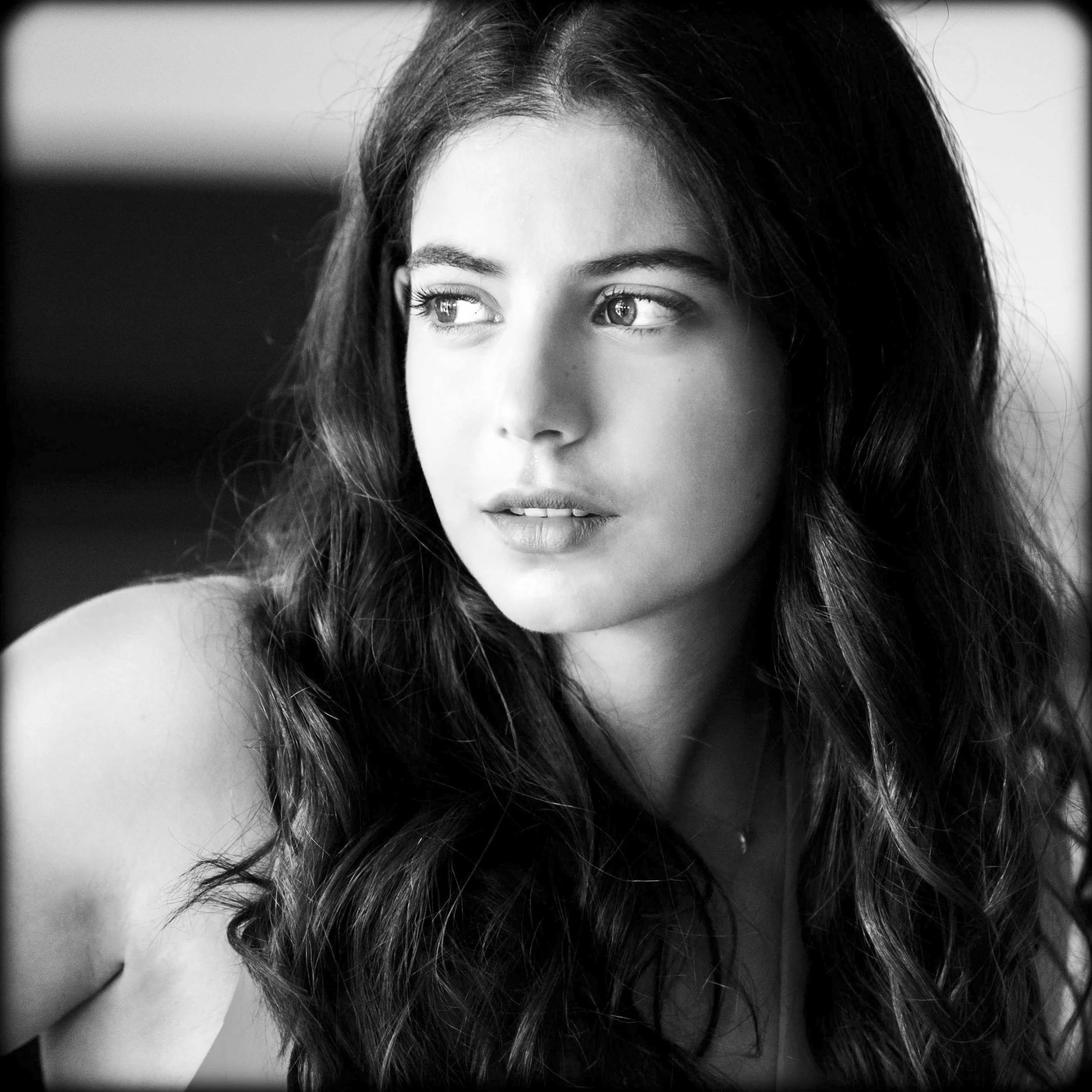 Black and white photo of a young woman with long wavy hair looking to her left.