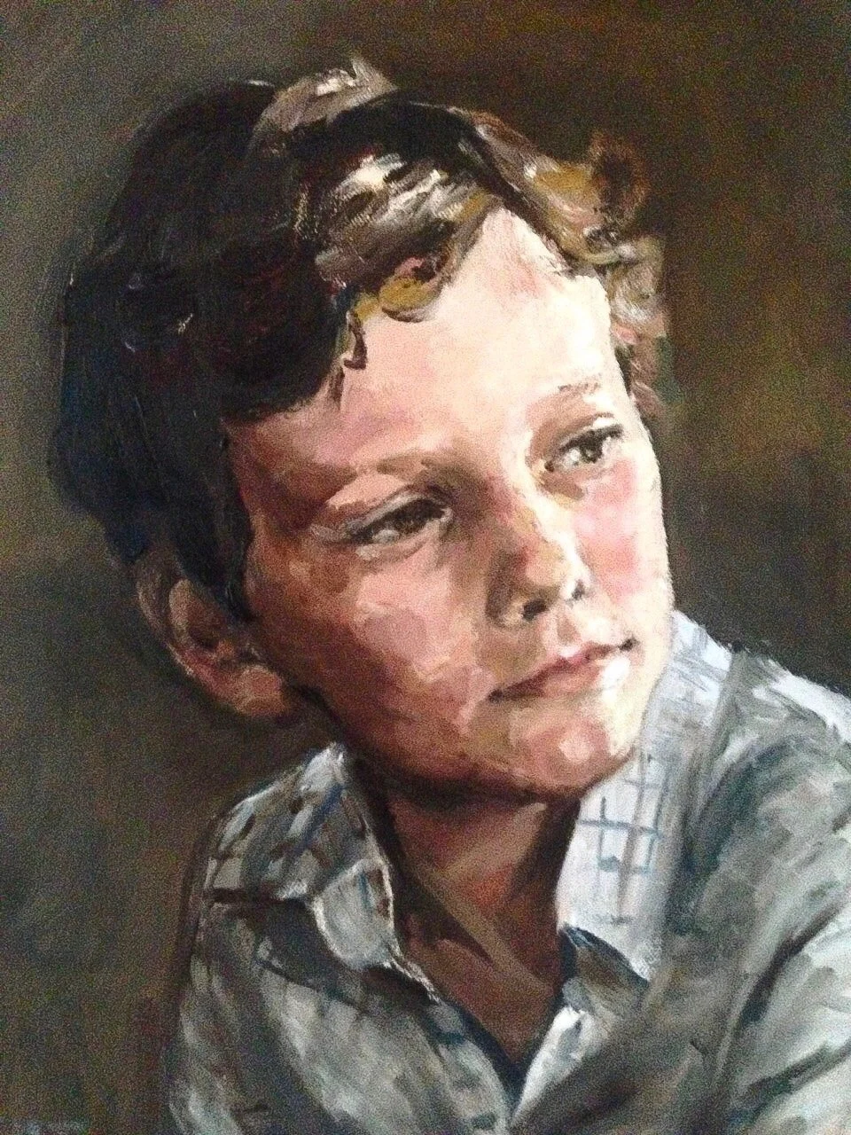 Modern wooden house with large glass window in a mountainous landscape with dry grass and small trees.