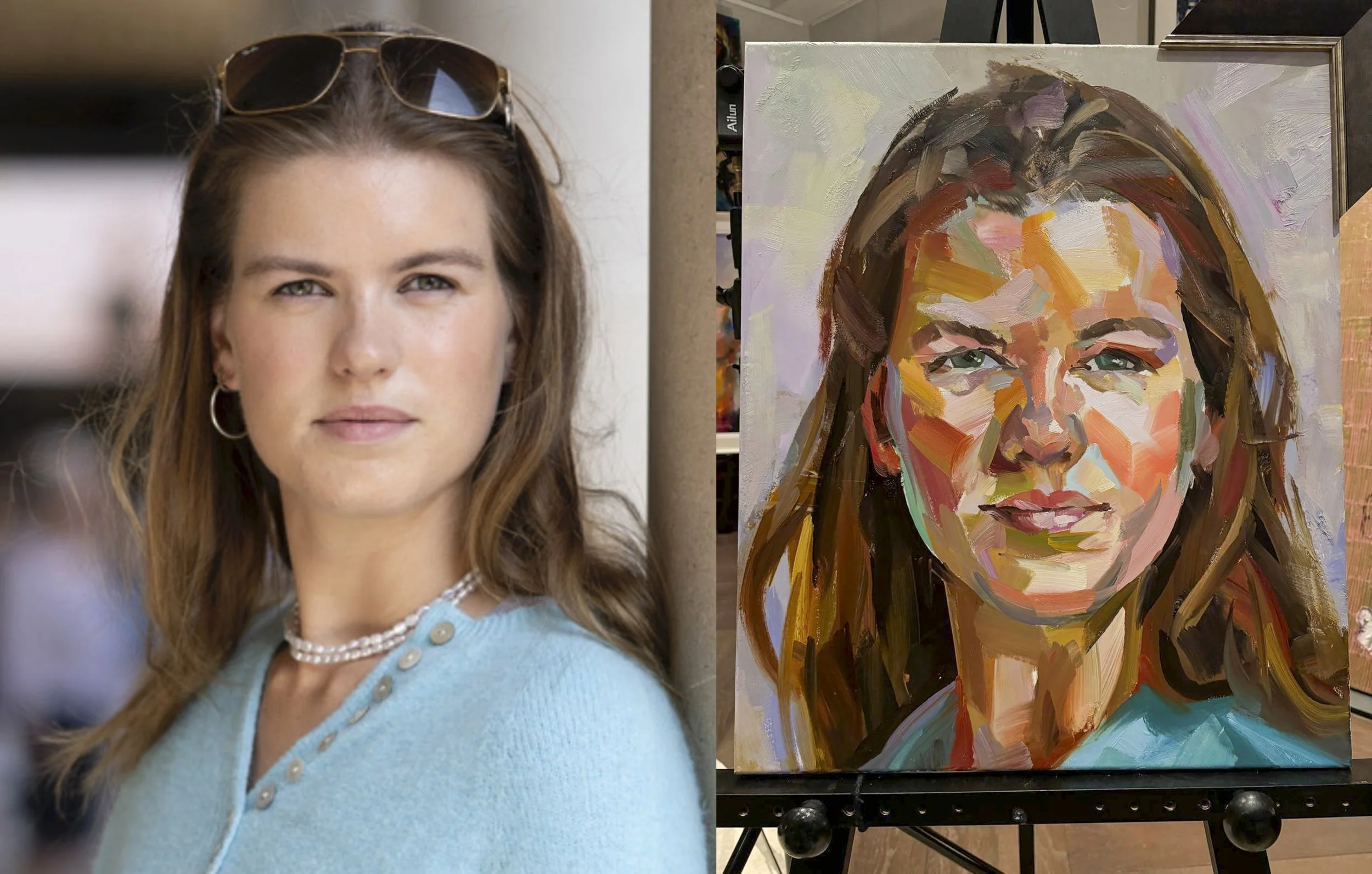 A living room with white walls, a cream tufted sofa with dark and gold pillows, a black coffee table with books and decorative items, a tall lamp on a side table, and a colorful portrait painting of a smiling man in a white t-shirt hanging on the wall.