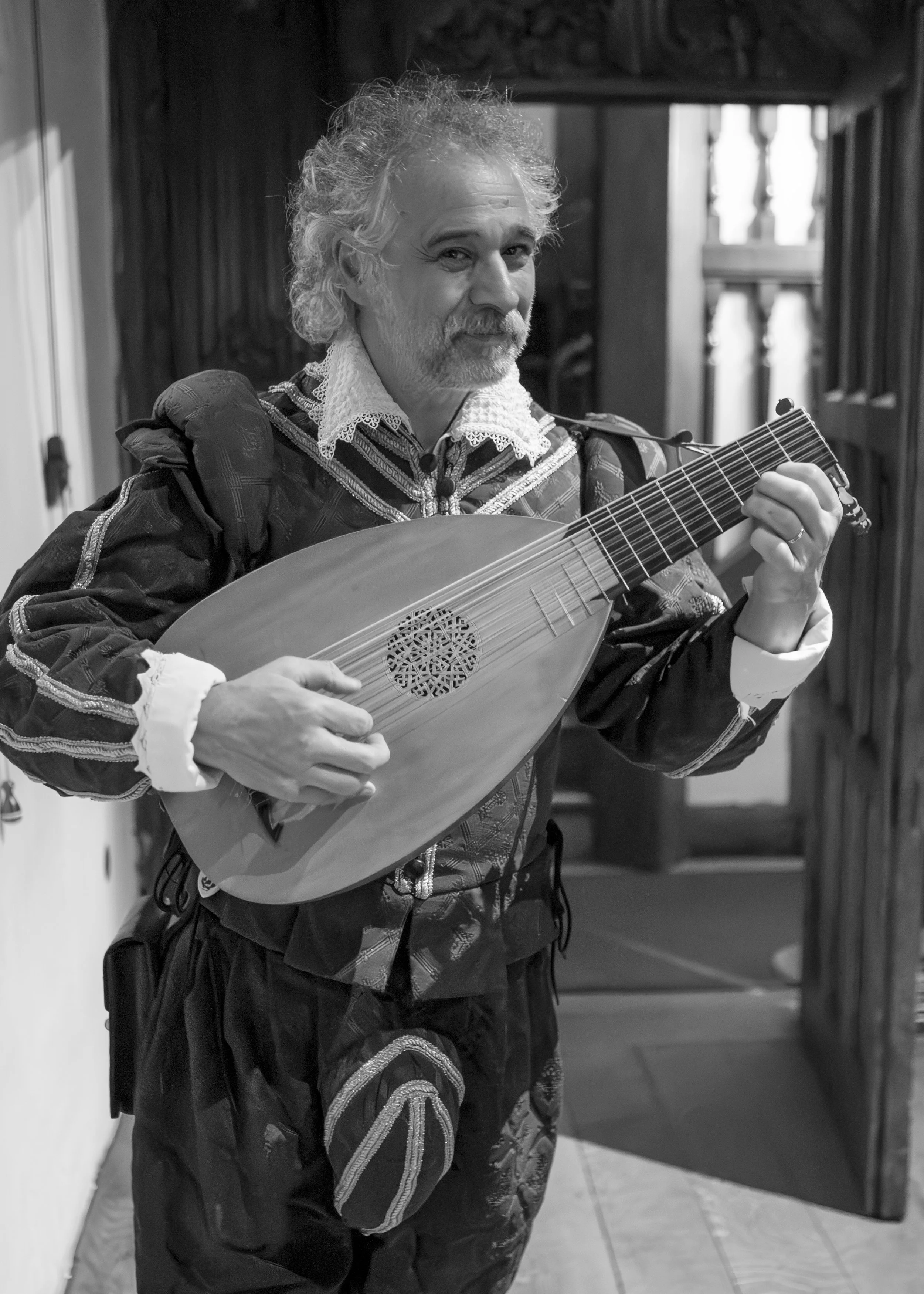 A man dressed in historic clothing playing a lute.