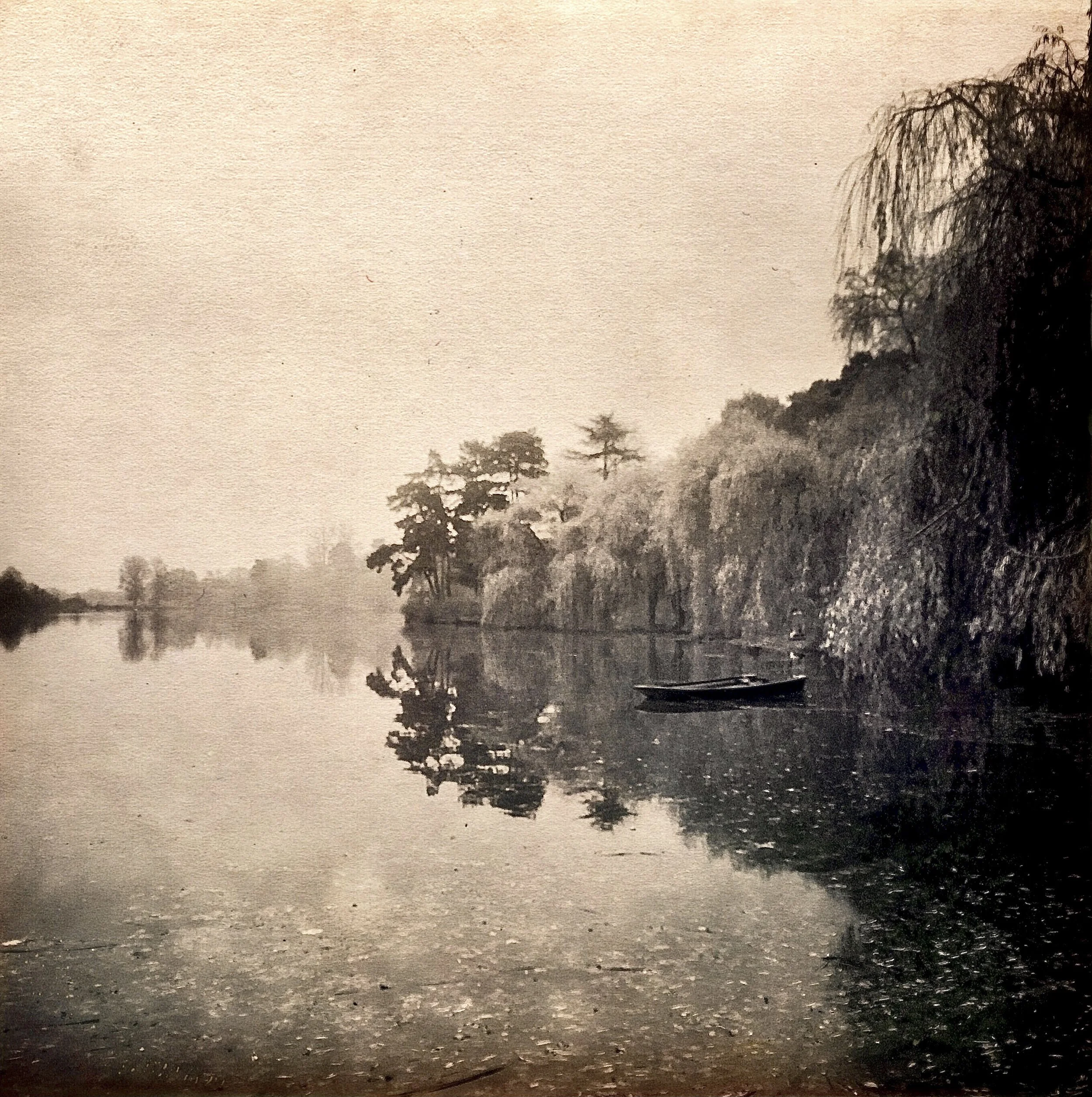 A calm river reflecting trees and cliffs on the shoreline, with a small boat floating on the water.