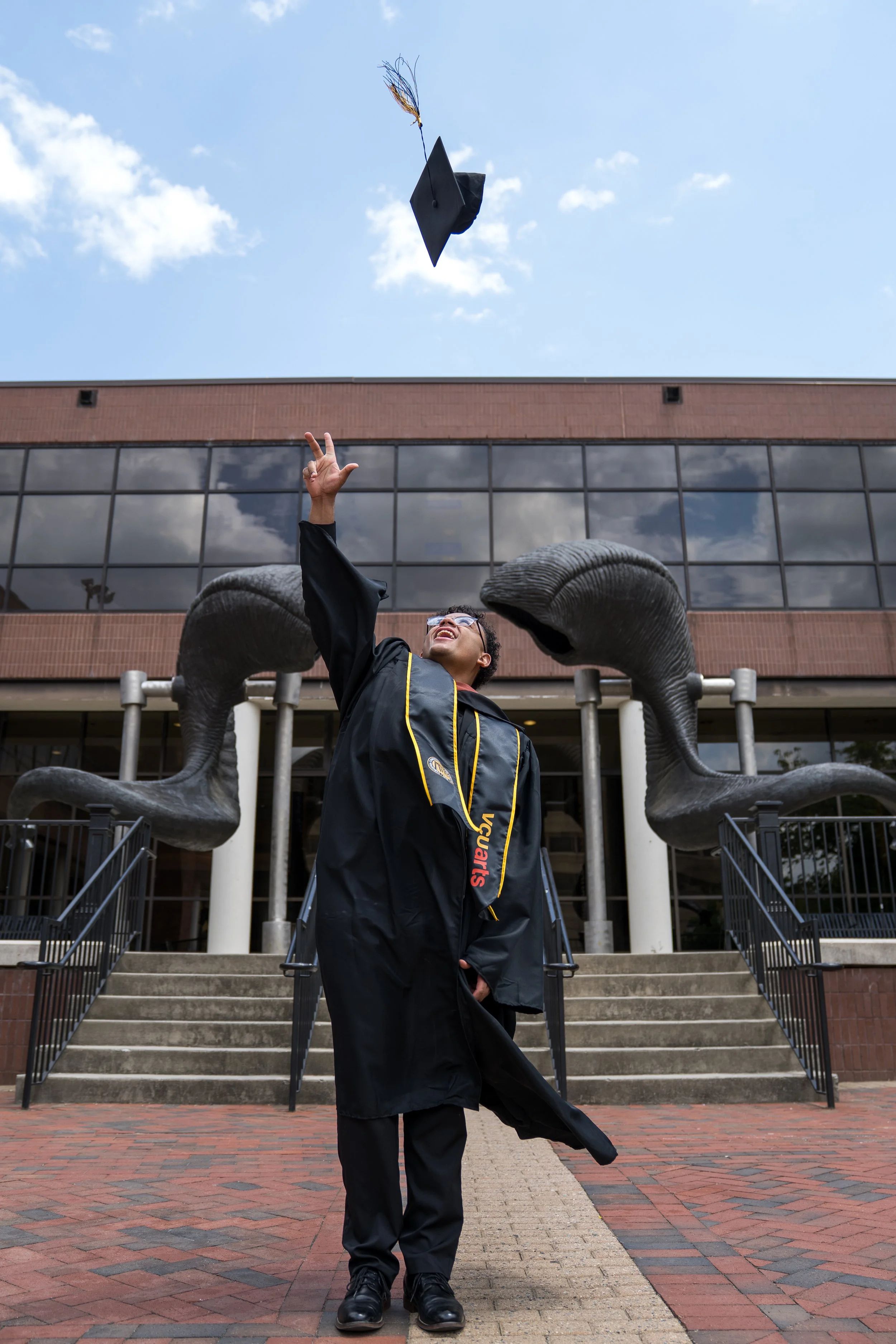 Alexander Scott Jr throwing his graduation cap into the air during a graduation photo session at Virginia Commonwealth University