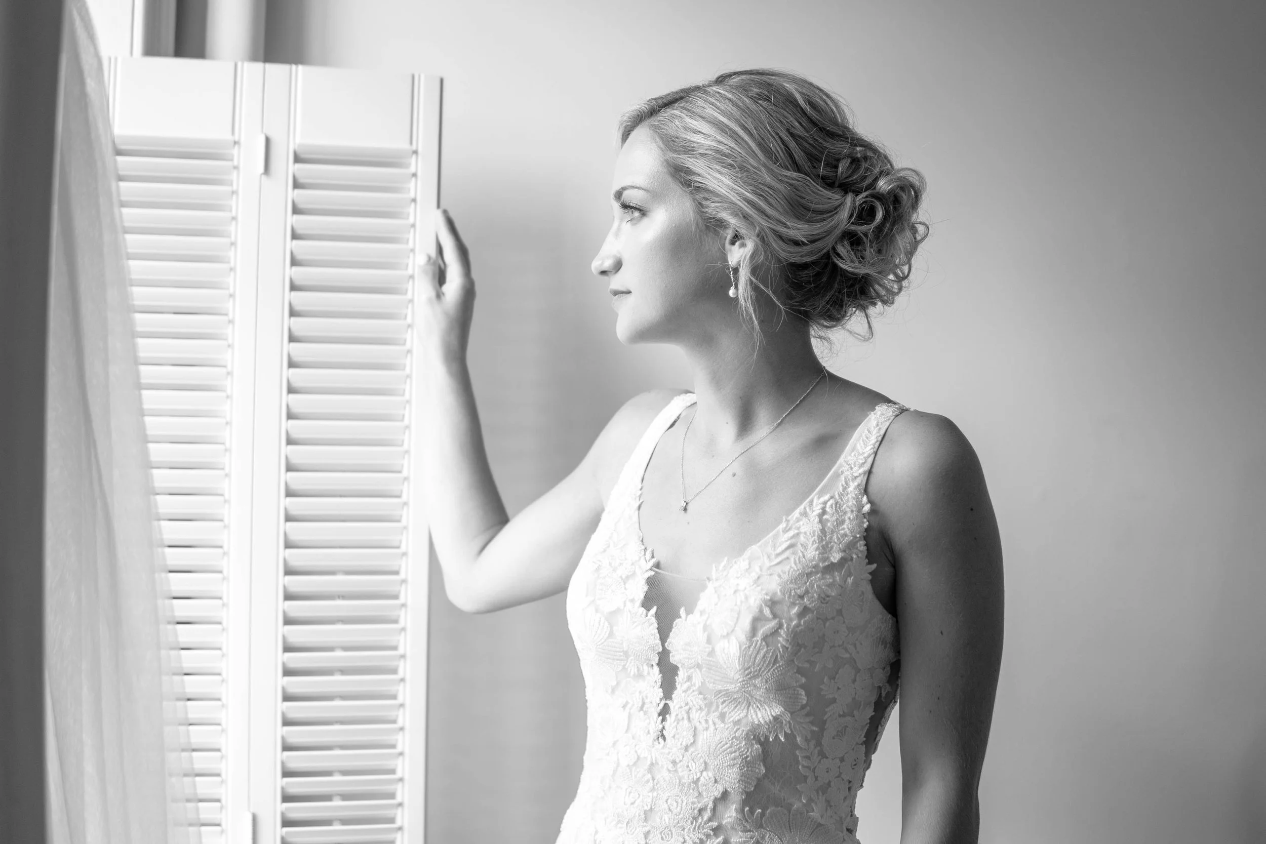 Black and white portrait of a bride looking out of a window