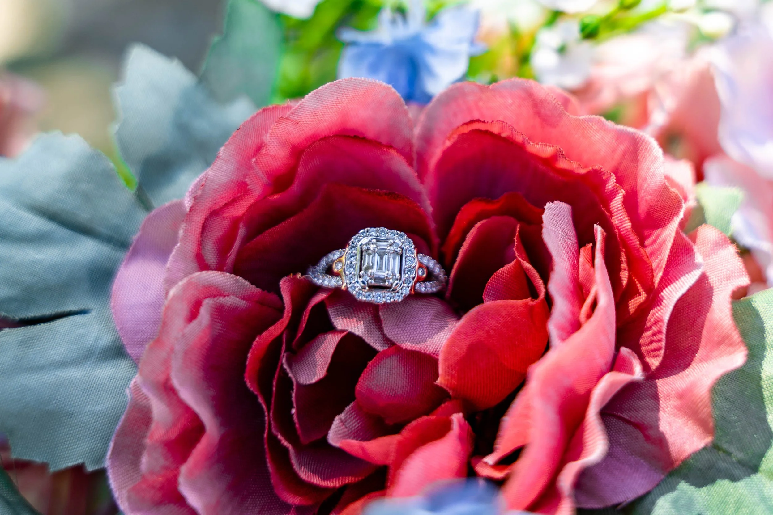 A wedding bouquet close-up with a diamond engagement ring in the center of a flower