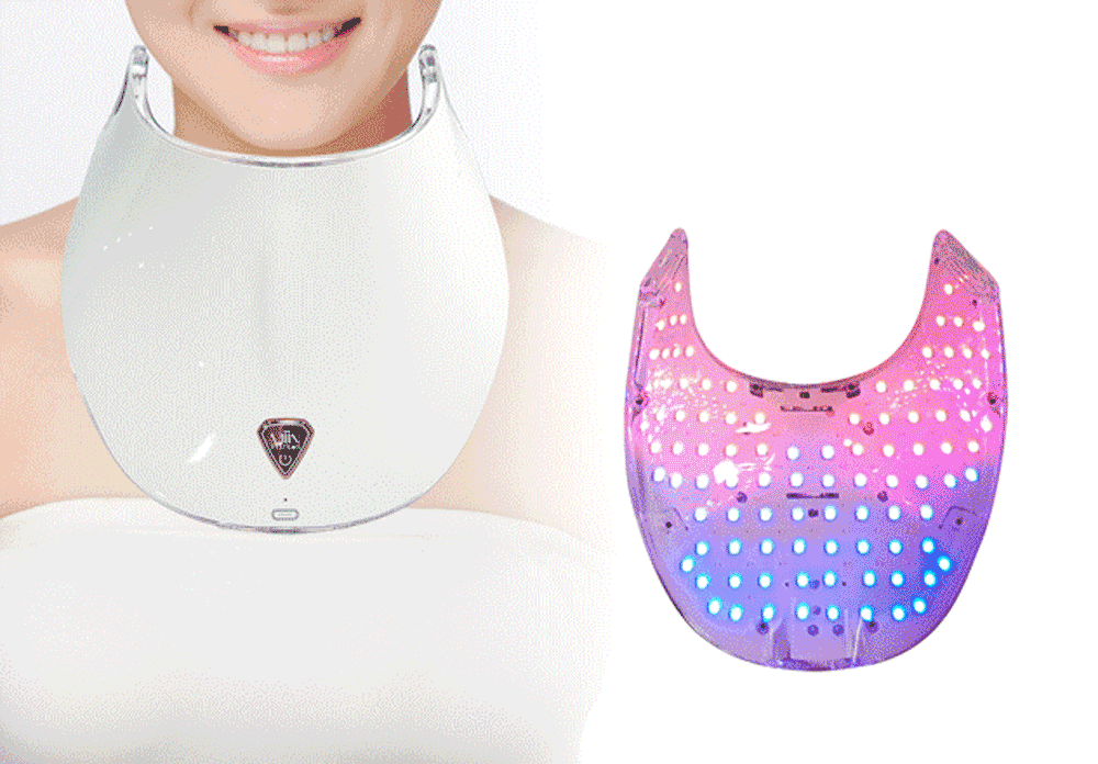 A person wearing a white LED facial mask, and a separate LED facial mask with pink and blue lights.