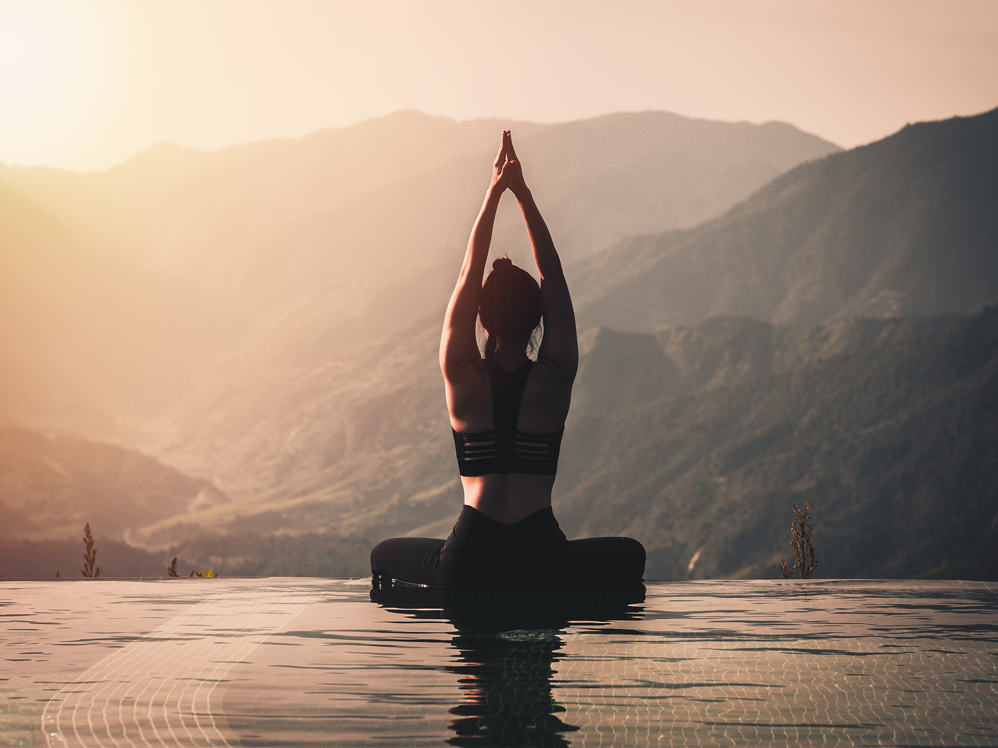 A female doing yoga while over looking the mountains during sun rise.