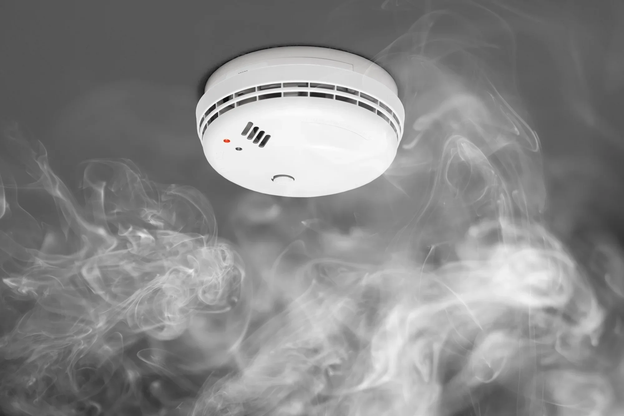 Smoke alarm on ceiling emitting smoke or vapor.