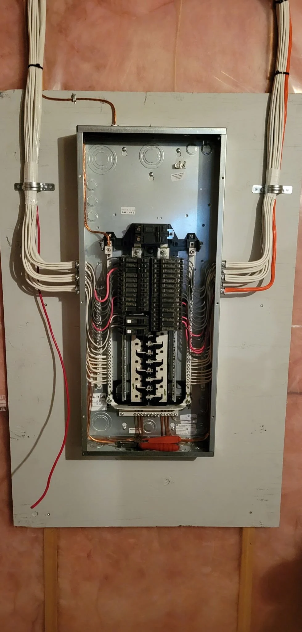 An open electrical breaker box with multiple wires connected to circuit breakers, mounted on a wall.