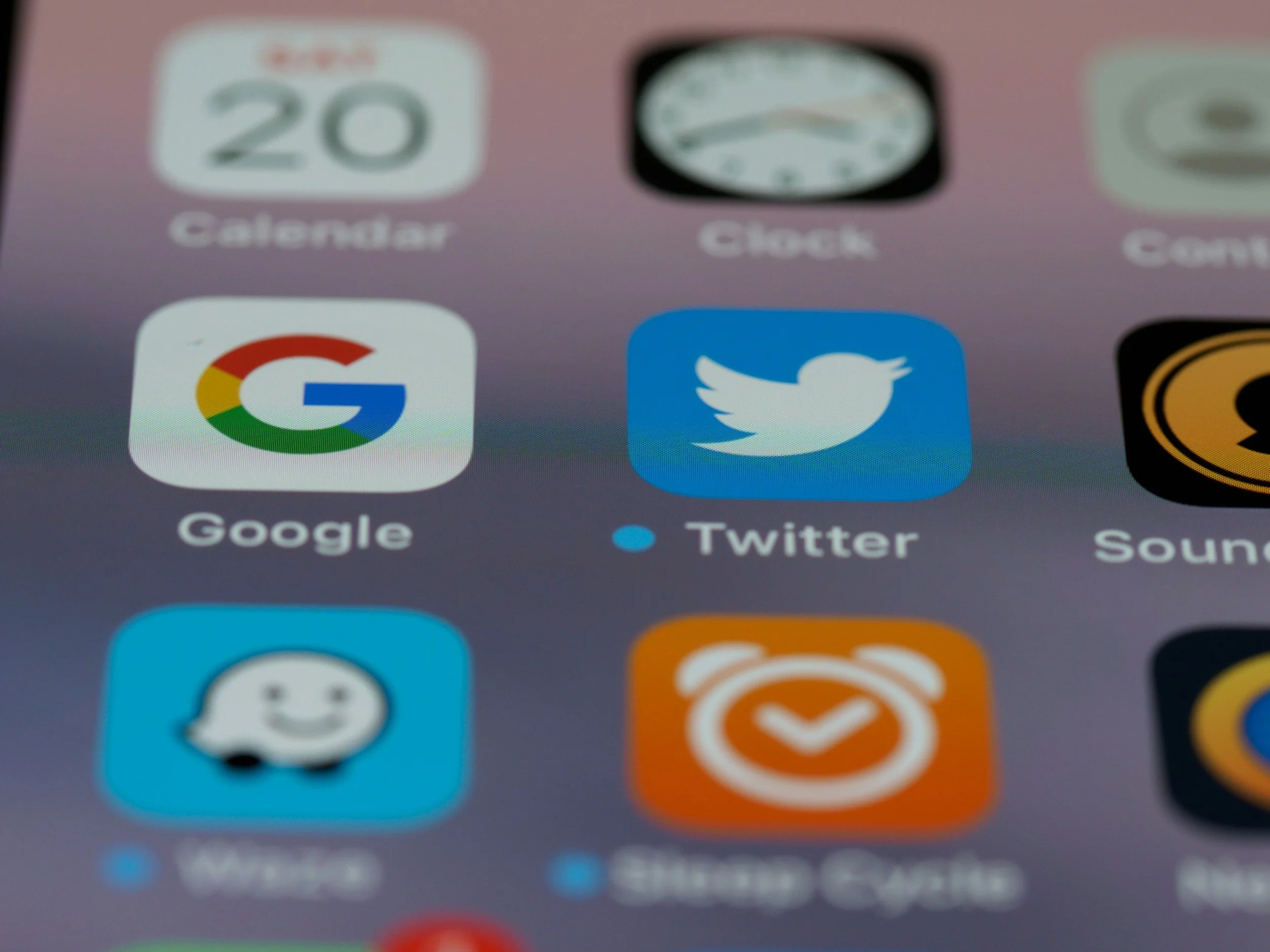 Close-up of a smartphone screen showing app icons, including Google, Twitter, and other apps.