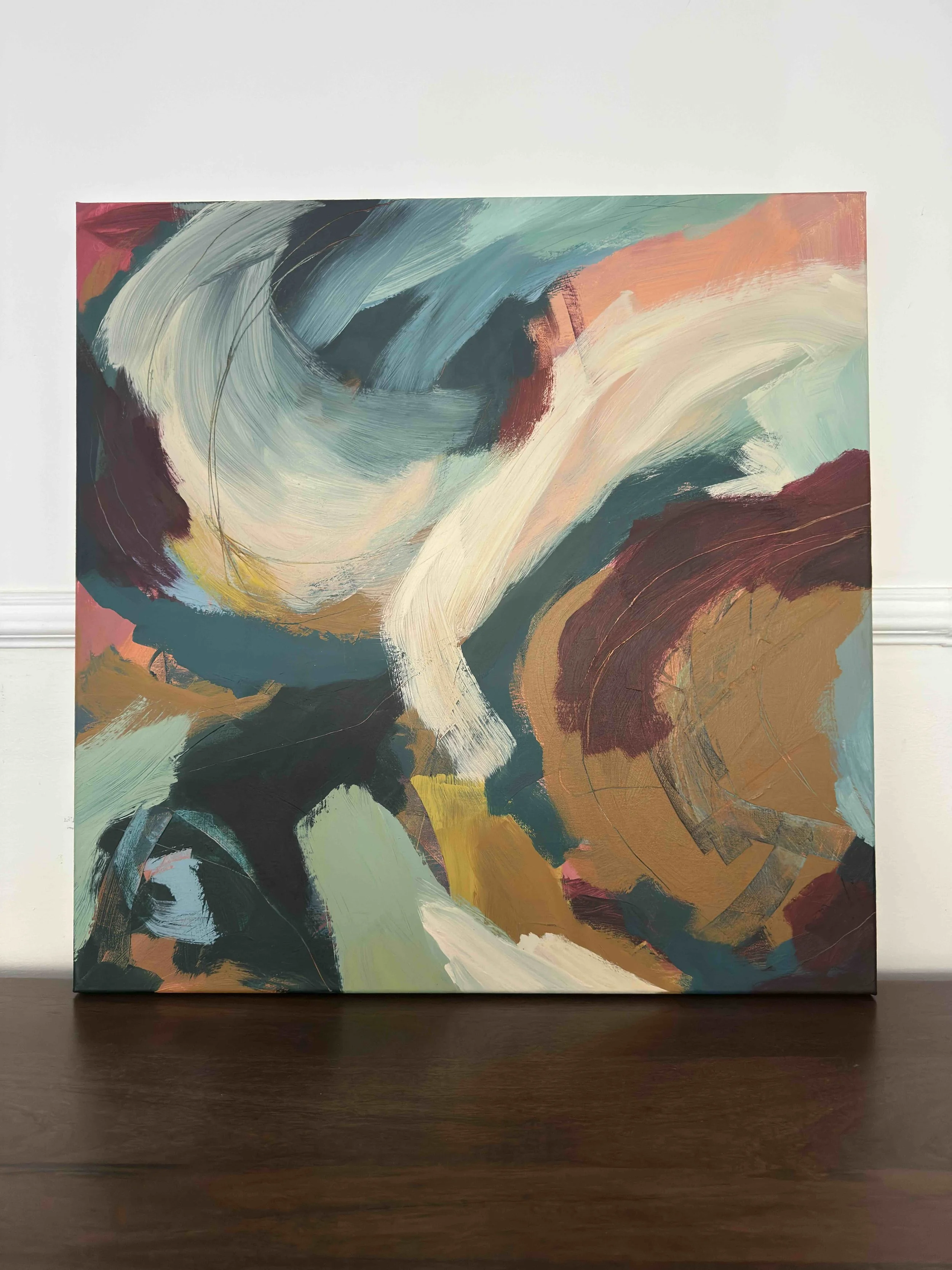 An abstract painting with swirling brushstrokes in shades of green, blue, white, brown, red, and pink, displayed on a white wall.