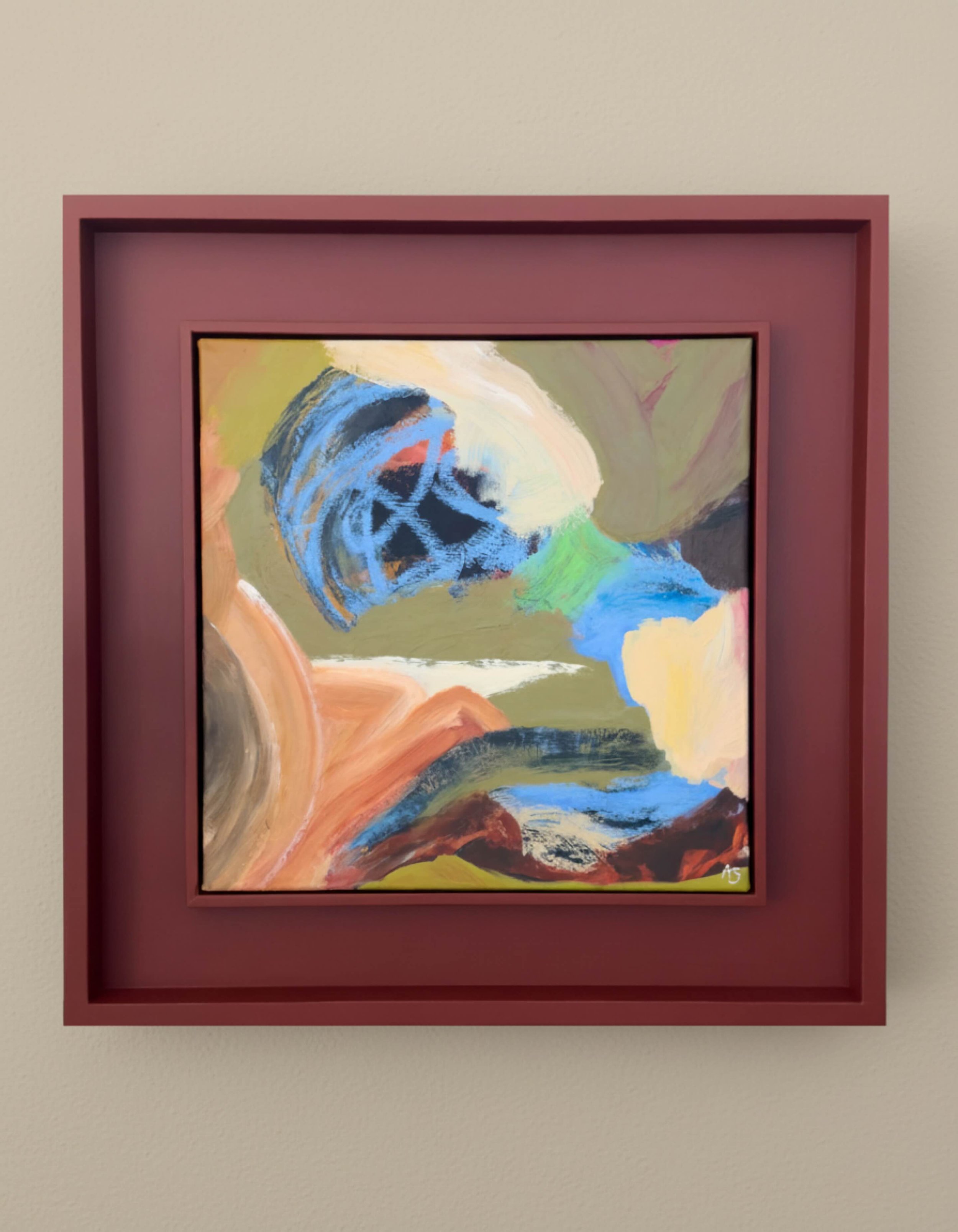 Abstract colorful painting in a pink frame on a beige wall.
