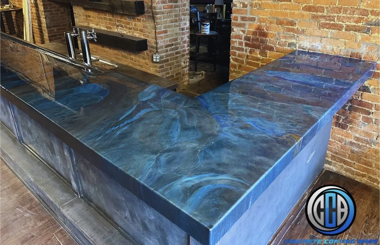 A bar counter with a blue and black swirling marble-like surface, situated against exposed brick walls.